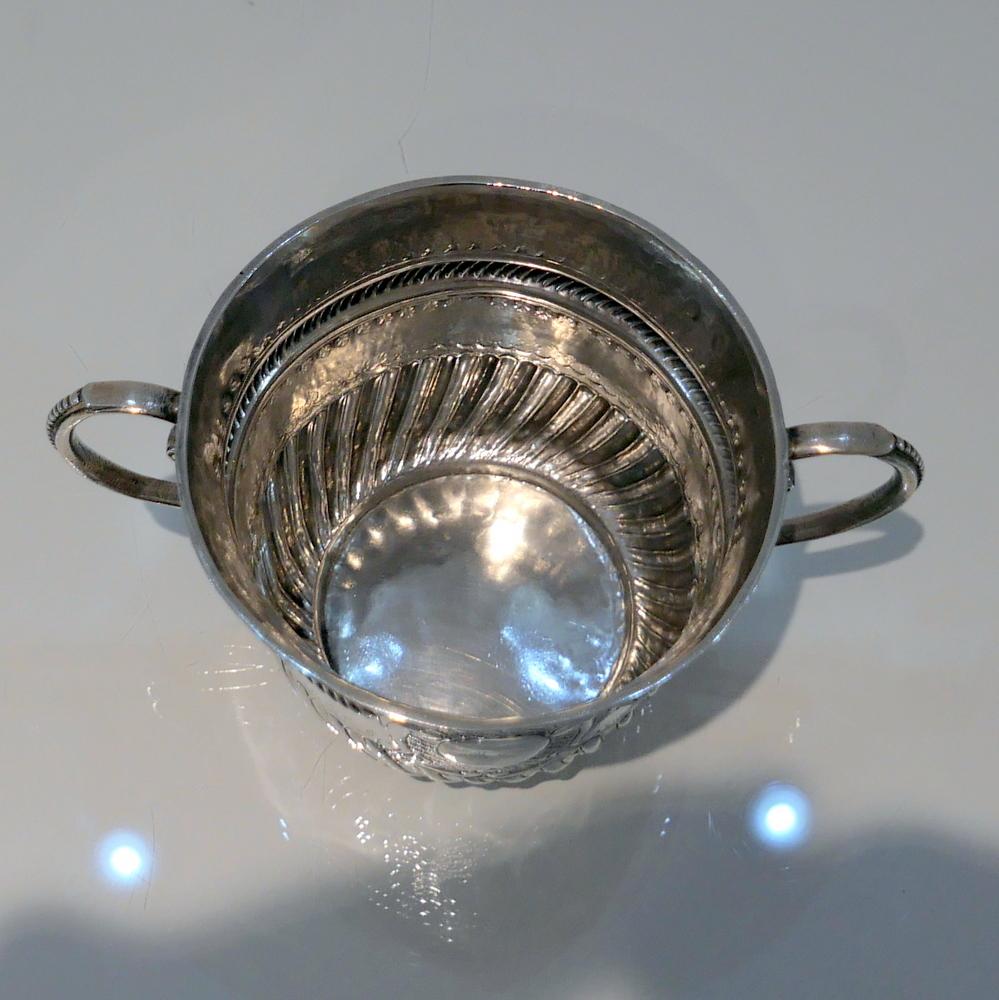 A fine Britannia standard porringer decorated with spiral fluting to the lower section and a elegant central matted scalloped cartouche in which sits contemporary initials for importance. There are two stylish applied bead wire handles for