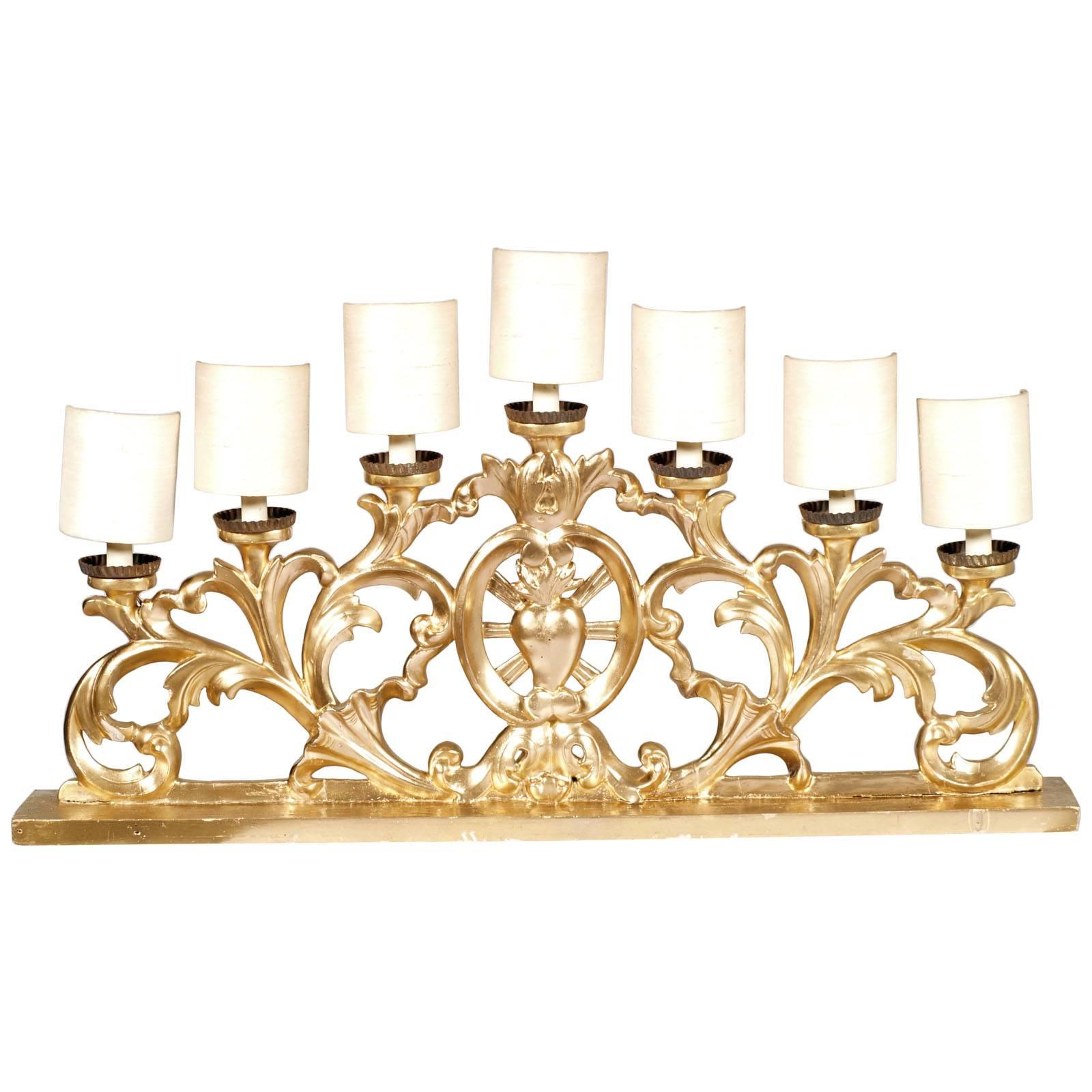 Chandelier baroque vénitien à sept lumières, indiqué pour une cheminée ou une crédence, en noyer sculpté à la main, finition feuille d'or, produit d'un chandelier du début des années 1700
Le cœur central sculpté, indique son origine
