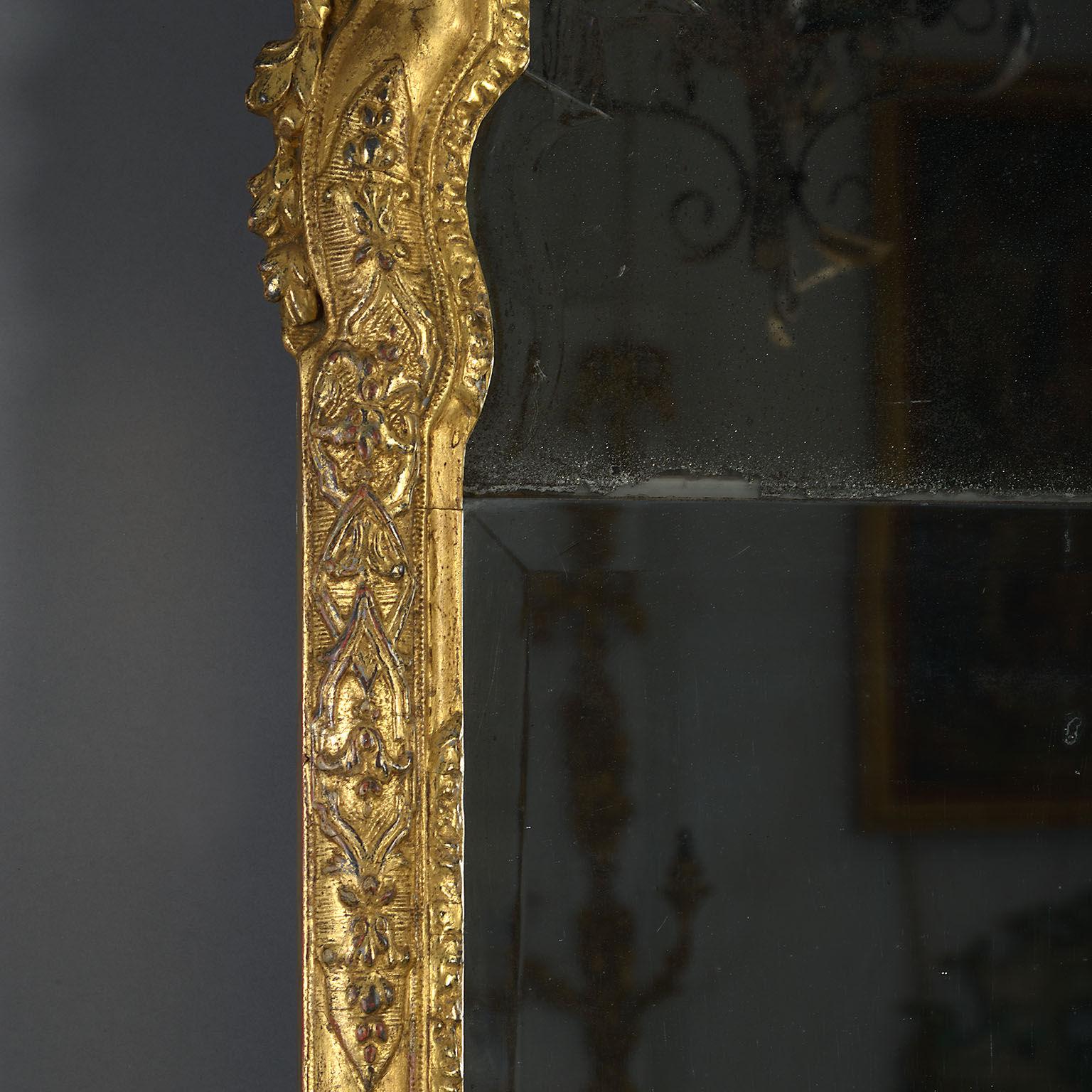 The original arched, divided plate with softly beveled edges contained within a molded frame carved with panels of strapwork, stylized foliage and scrollwork and with a lambrequin cresting.