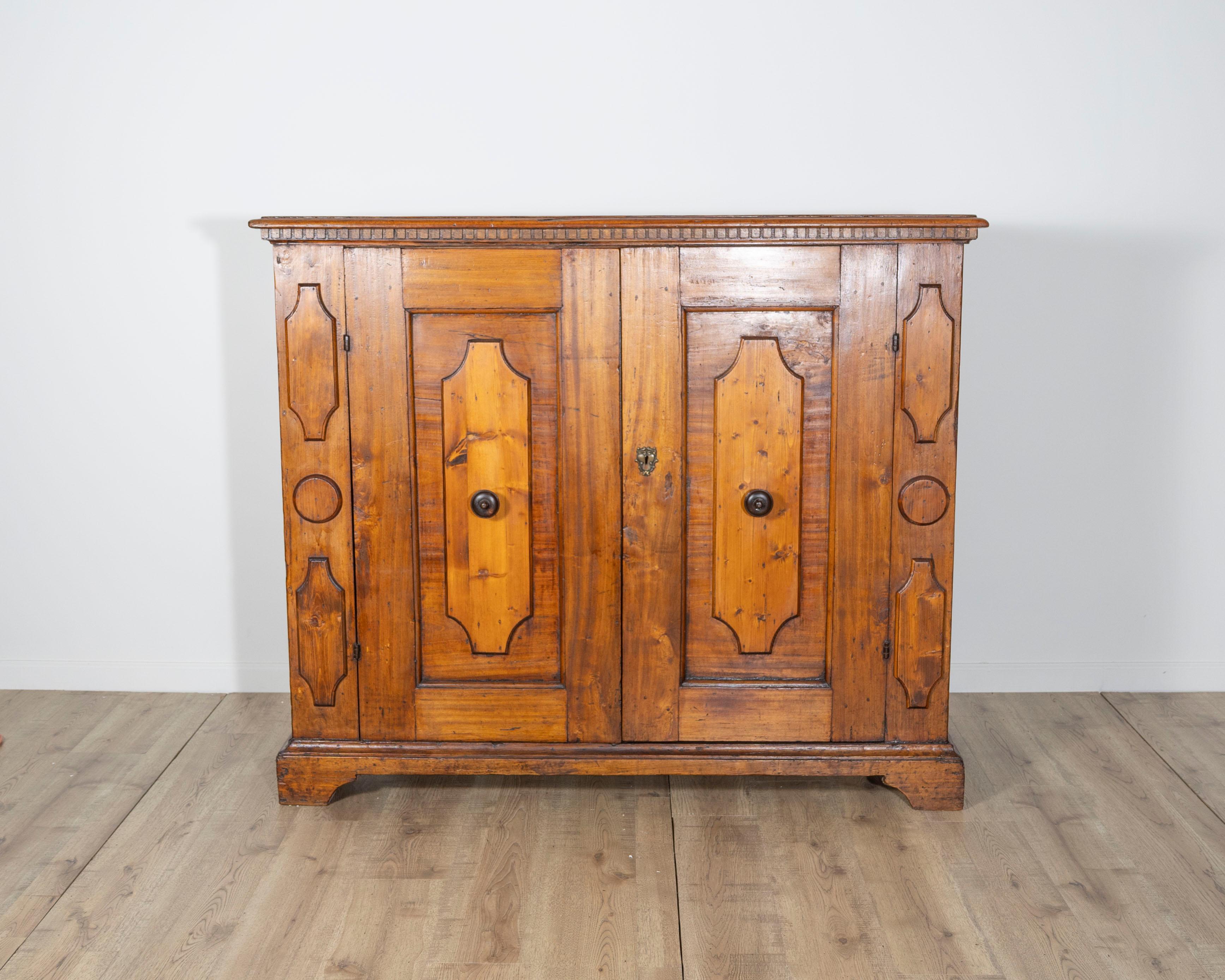 A rare and handsome Bolognese sideboard from the early 18th century, crafted in solid walnut with a warm, aged patina that highlights the wood’s natural grain and depth. This substantial piece features two paneled doors with decorative geometric