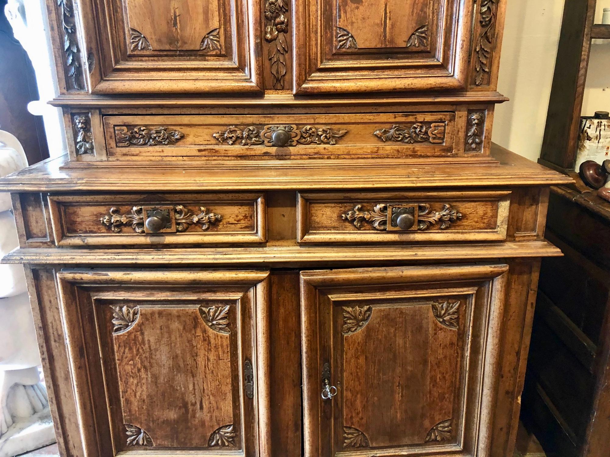 This is a rare period walnut French buffet Deux corps from the Provence region of France. It has a deep, rich patina along with deep carvings and motifs with worn reliefs, showing its 300 year old age. Superb carvings to the top and door