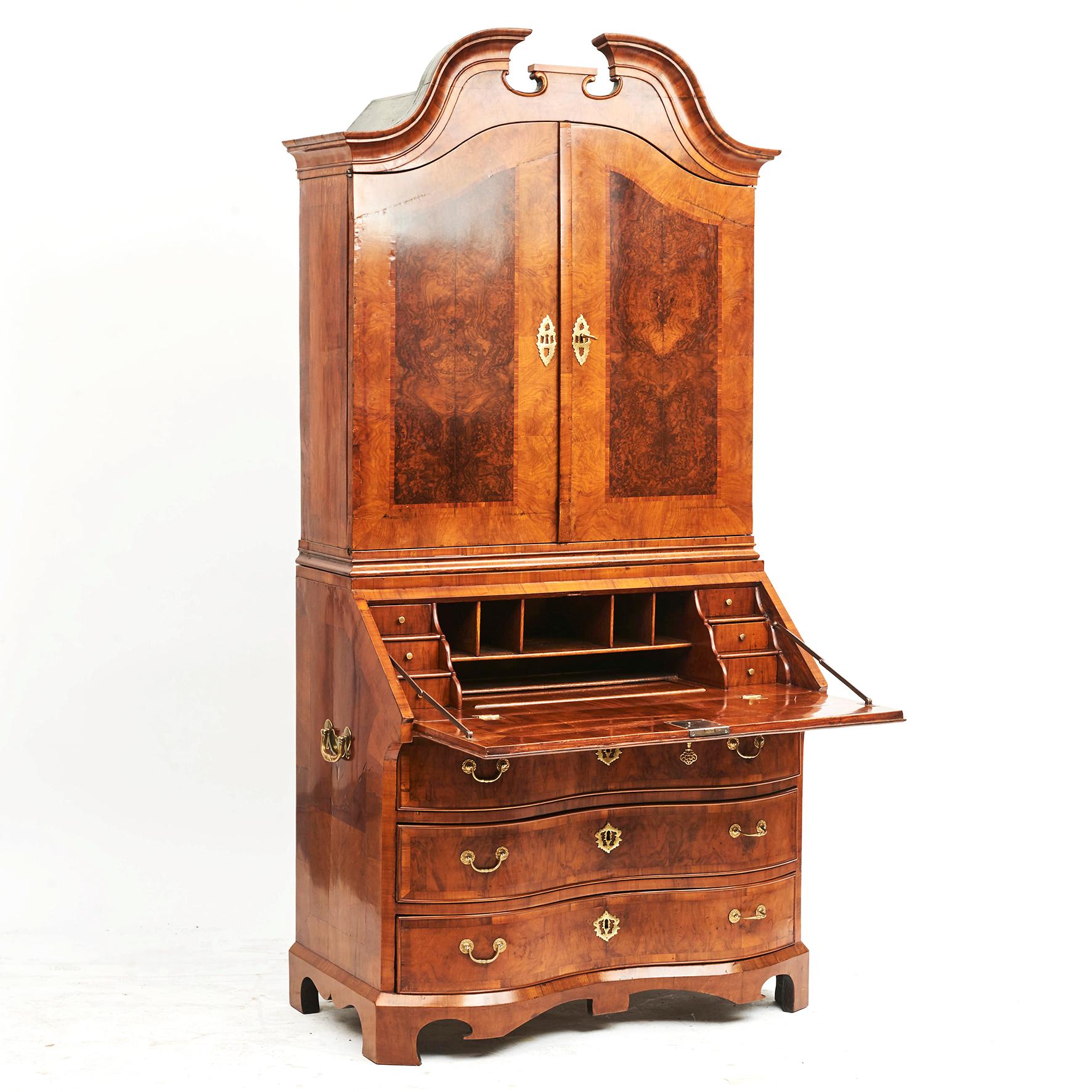 Early 18th century burl walnut veneered bureau cabinet.
The upper section with swan neck top over double doors, the lower section with a sloping-front opening to reveal a cupboard and six small drawers.
Original locks and hardware.

Denmark or