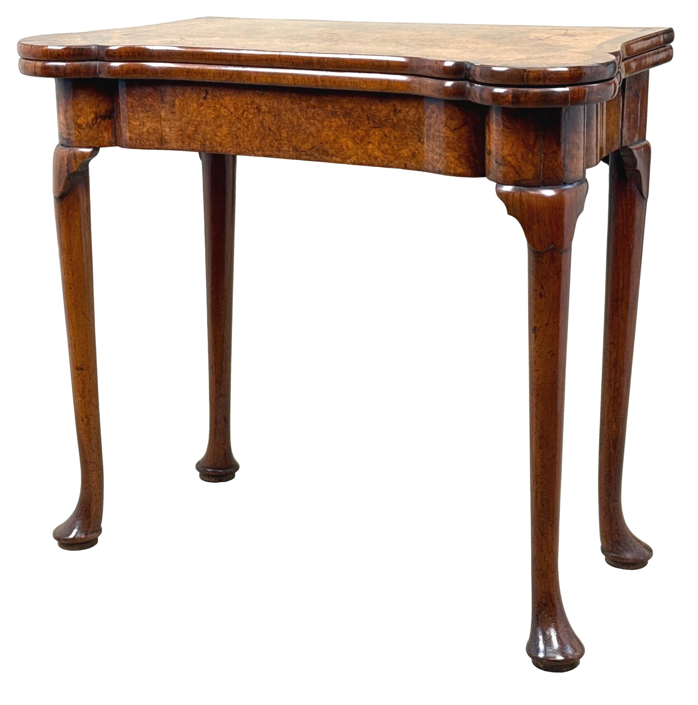 Estremamente raro tavolo da gioco in radica di noce dell'inizio del XVIII secolo, periodo Giorgio I, che conserva un meraviglioso colore e una patina intatti in tutto il suo insieme, con il piano a ribalta superbamente figurato con decorazioni a