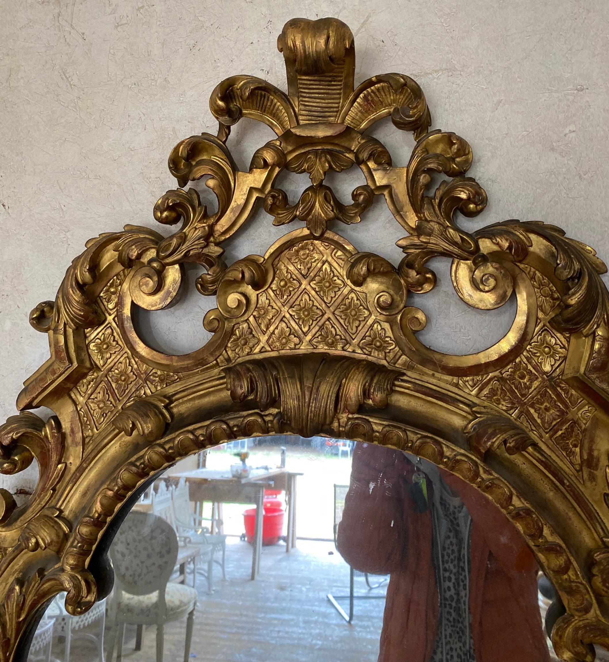 A rare large early 18th century Continental gilt-wood pier mirror with gilt frame the crest with a flamboyant decoration around a frame. Antique split mirror plates shows aged distress with some dark spots in areas giving it character and more