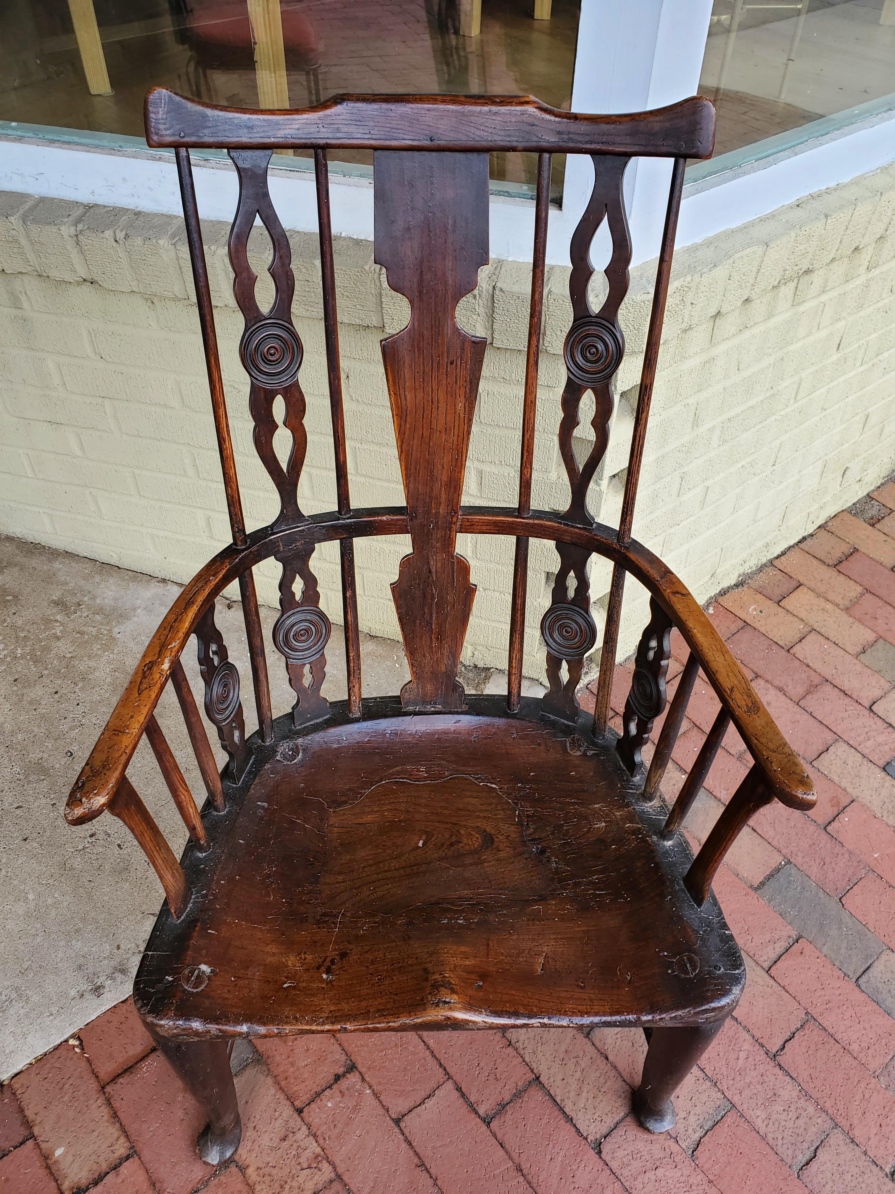 This rare early 18th century English “comb-back” Windsor armchair, made of ash, elm, and walnut, has a beautifully deep lustrous color. Delicate spindles with five uniquely shaped splats with pierced and turned decoration. Elegant curved arms over