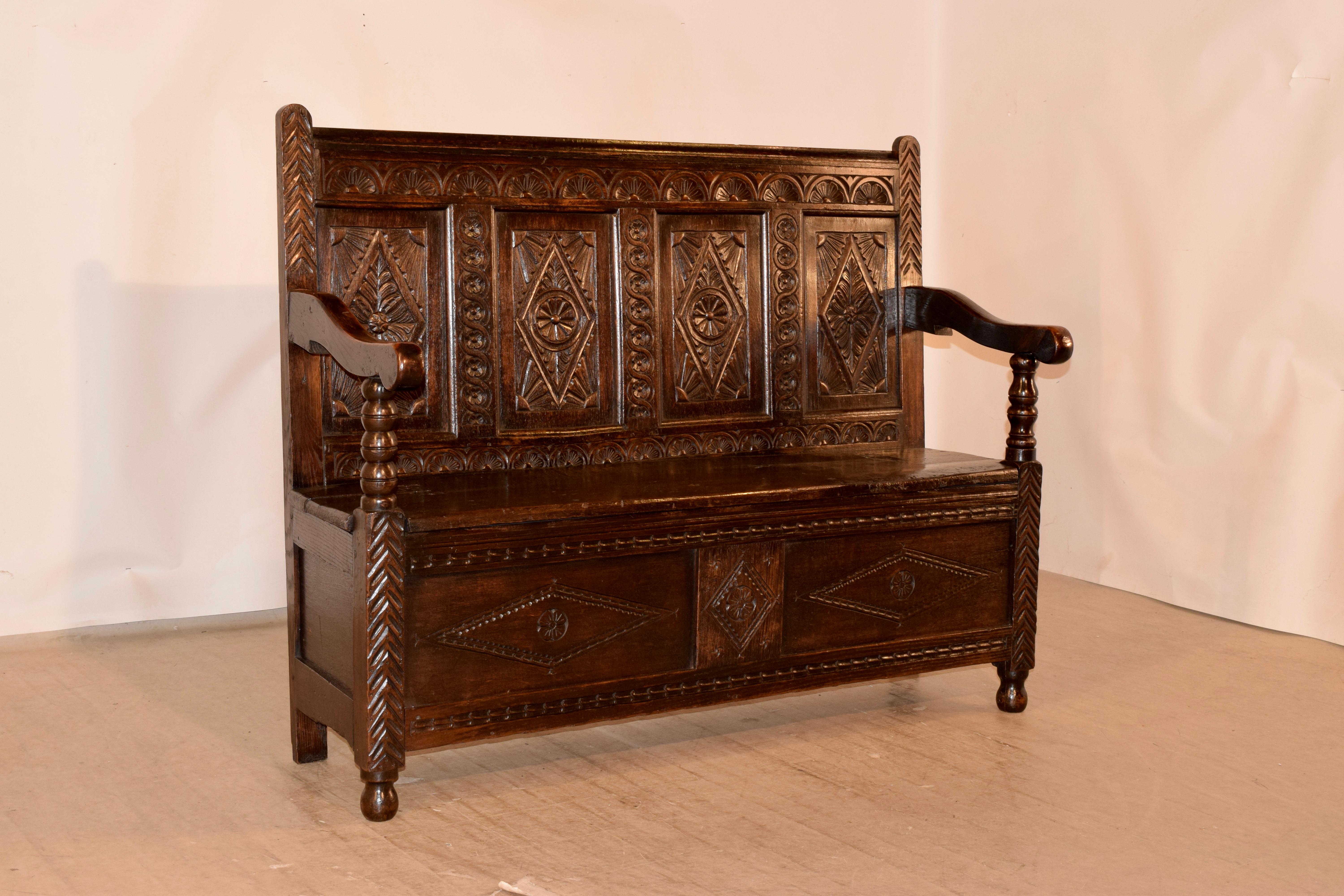 c. 1720 English oak bench with a wonderfully hand carved decoration. The top is decorated with hand carved lunettes, following down to four panels, all with carved cartouches surrounded by accented carvings, flanked by guilloche carvings, over