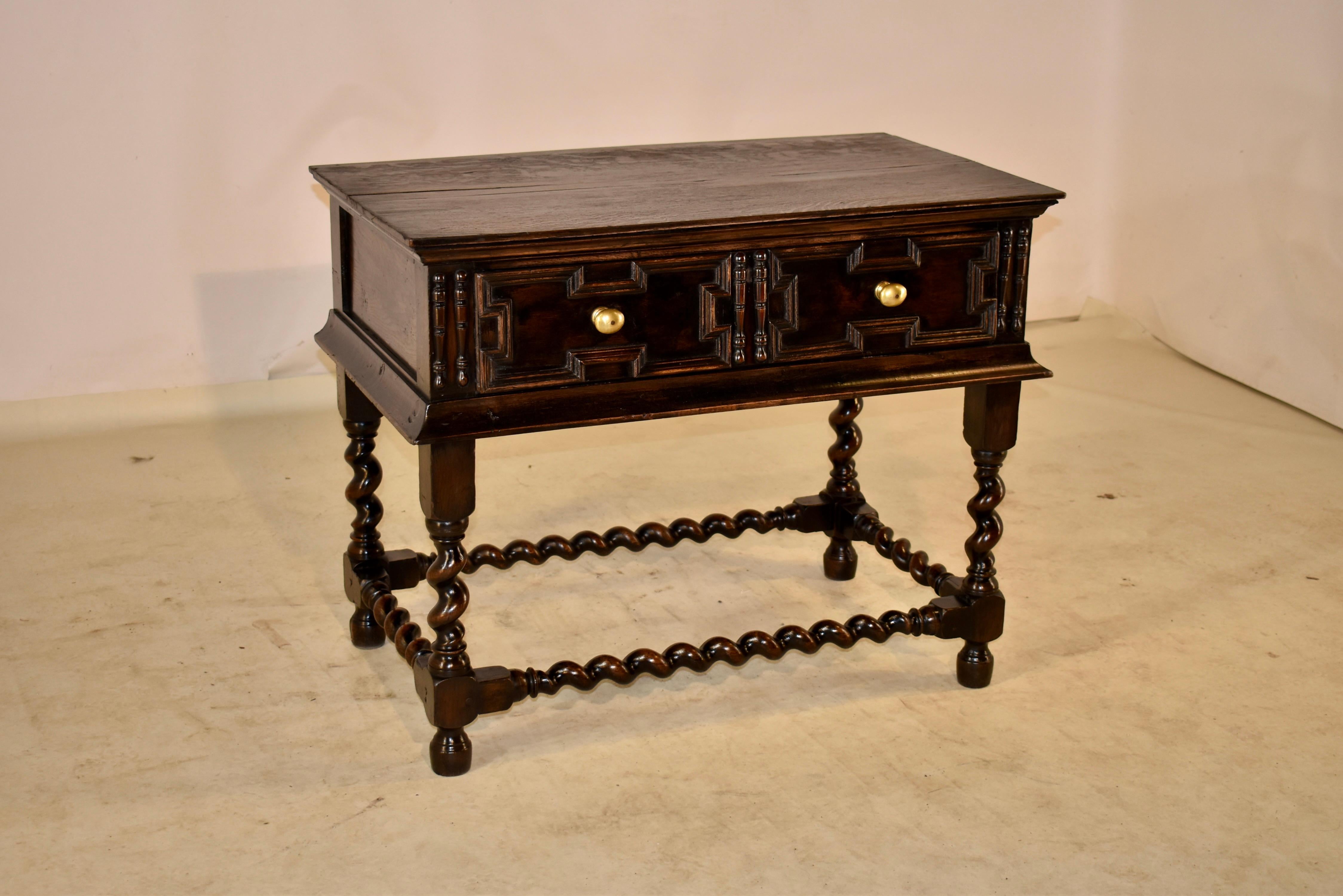 Early 18th century oak table from England with hand paneled sides and a single drawer in the front, which also has hand applied geometric molding. The drawer is flanked by applied turnings and has a molded apron below. The table is supported on hand