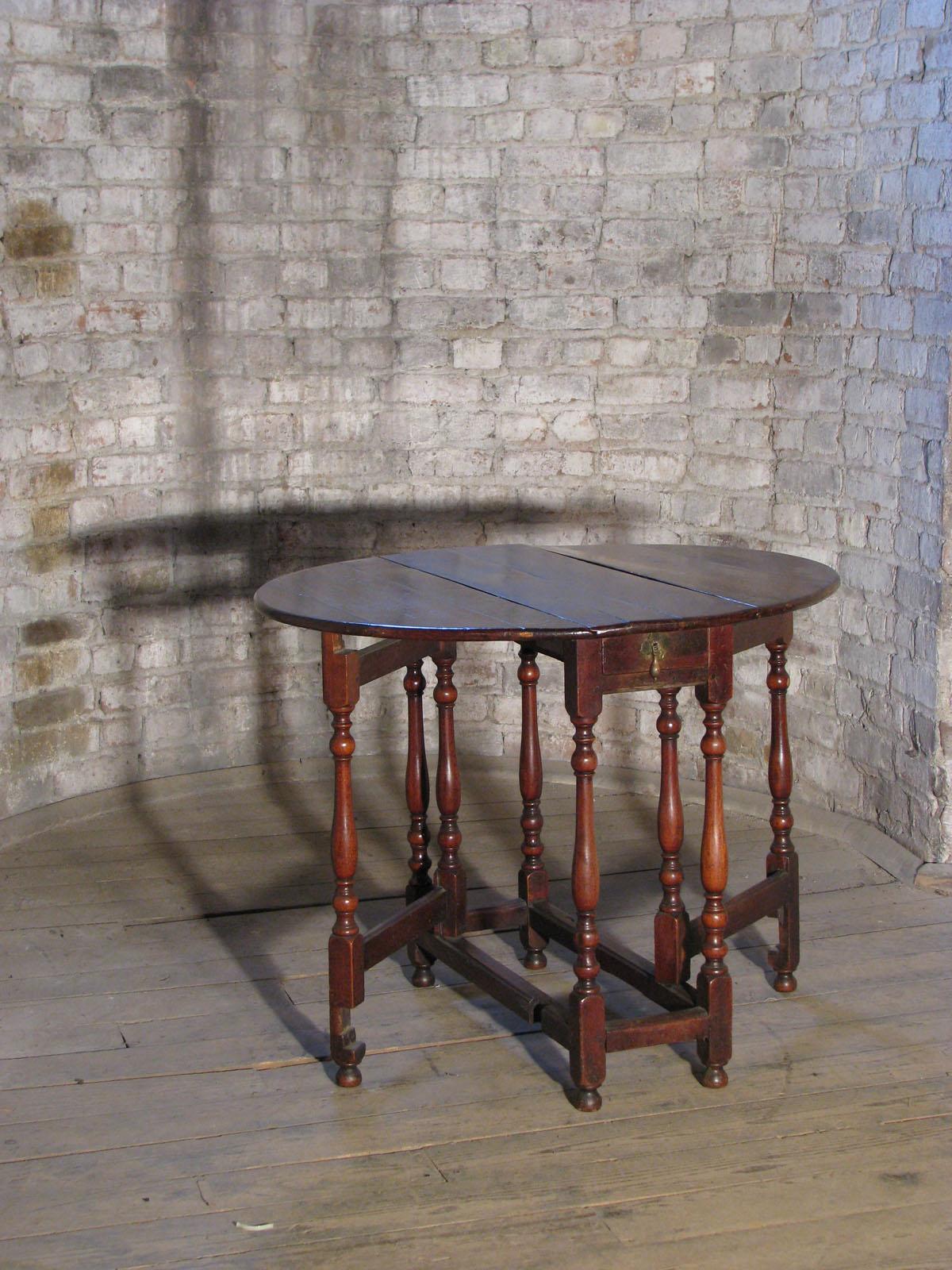 Elegant, delicate and versatile English Queen Anne Dropleaf / Gateleg Table of slightly oval form. Suited for various functions, it can be used as small wall-console, narrow end table or, with both leaves open, as end or center table. The top, above