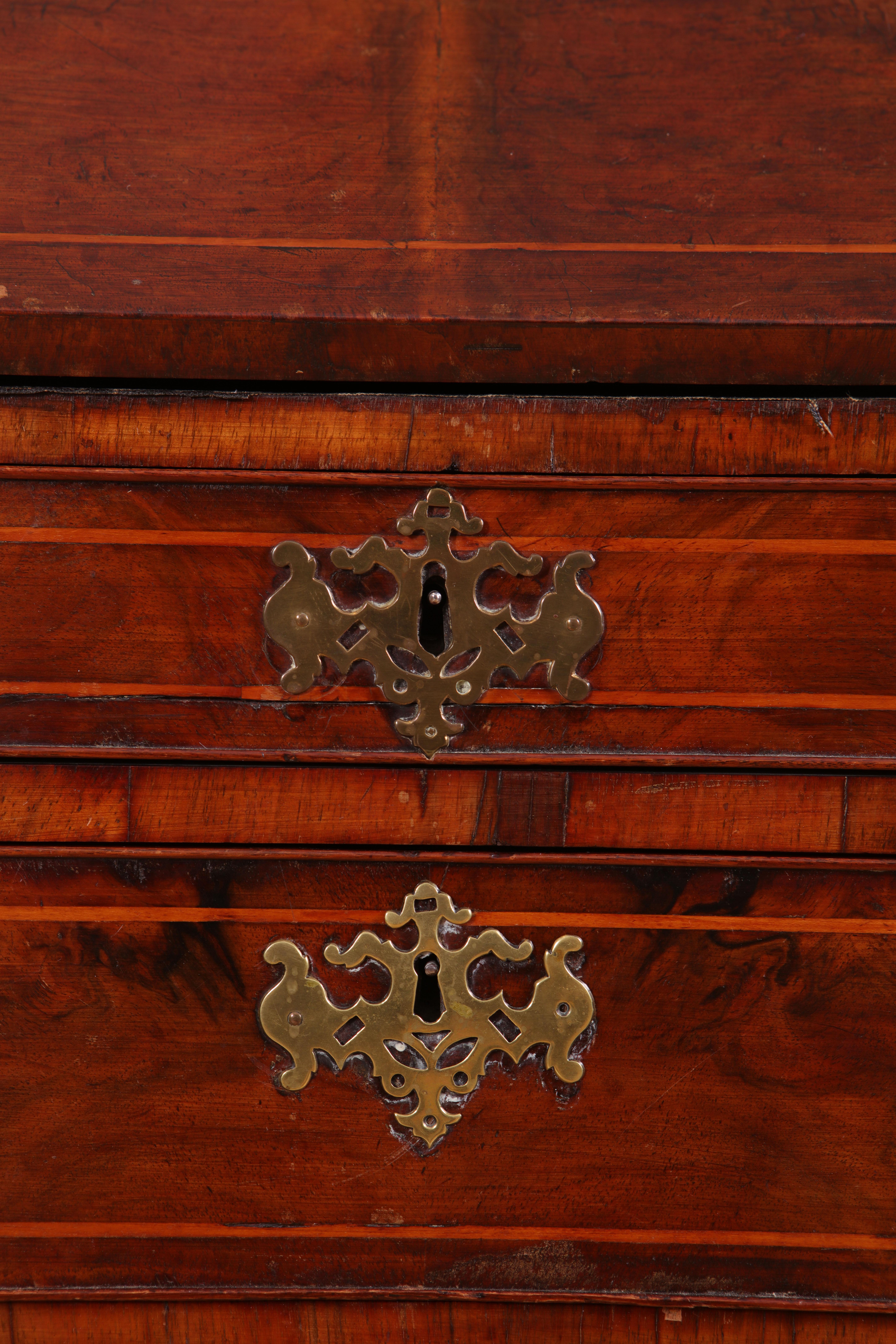 A fine early Georgian walnut secretaire cabinet veneered throughout with book-matched figured walnut. The fall front opening to a fitted interior of drawers and pigeon holes with ogee ornament, the slope resting on pull-out bearers. Below are four