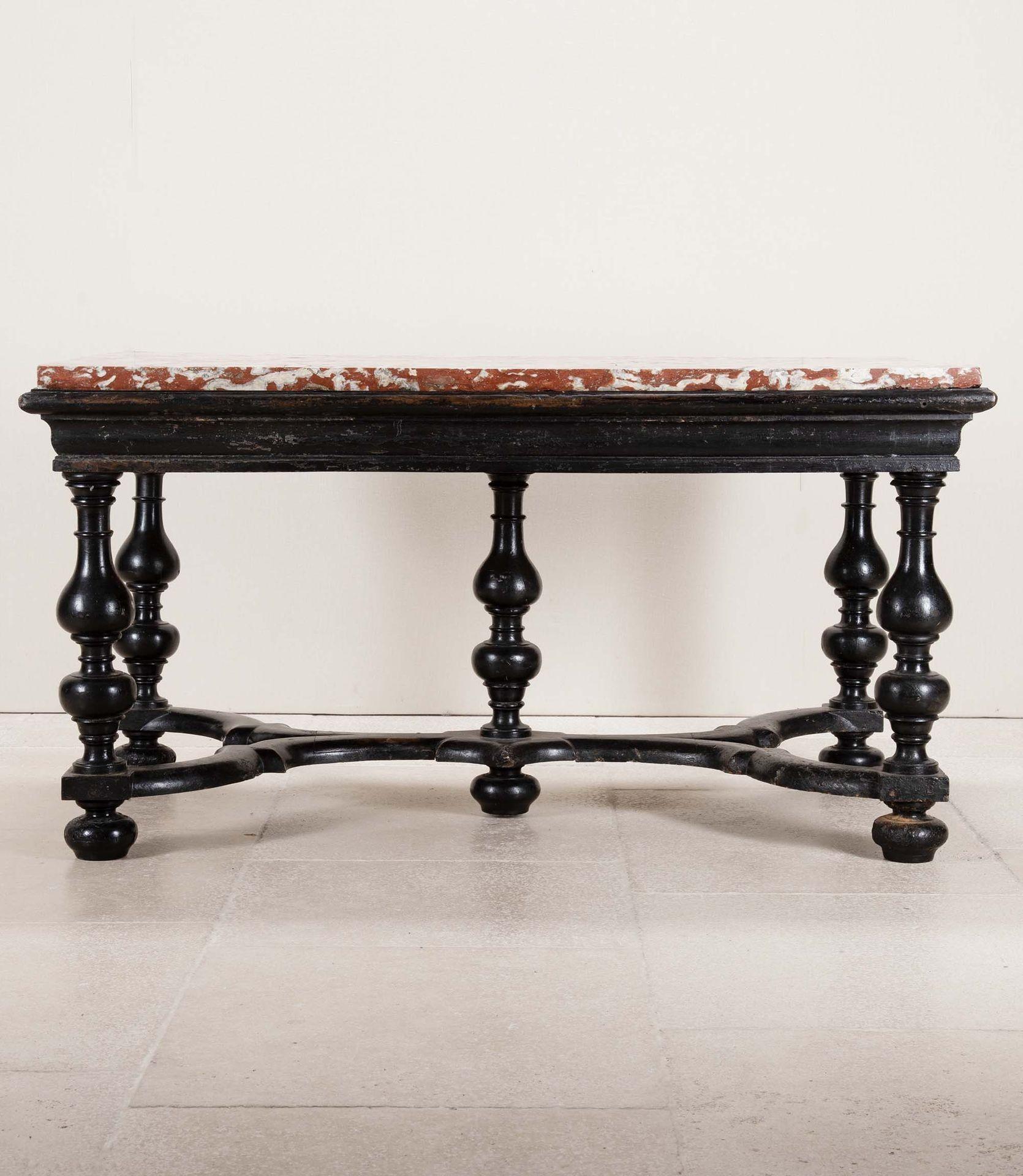Table centrale de la fin de la période Louis XIV ou Régence. Probablement originaire du sud-ouest de la France, la base ébonisée de cinq pieds élégamment tournés est unie par un audacieux châssis en X, l'ensemble supportant un original et stupéfiant