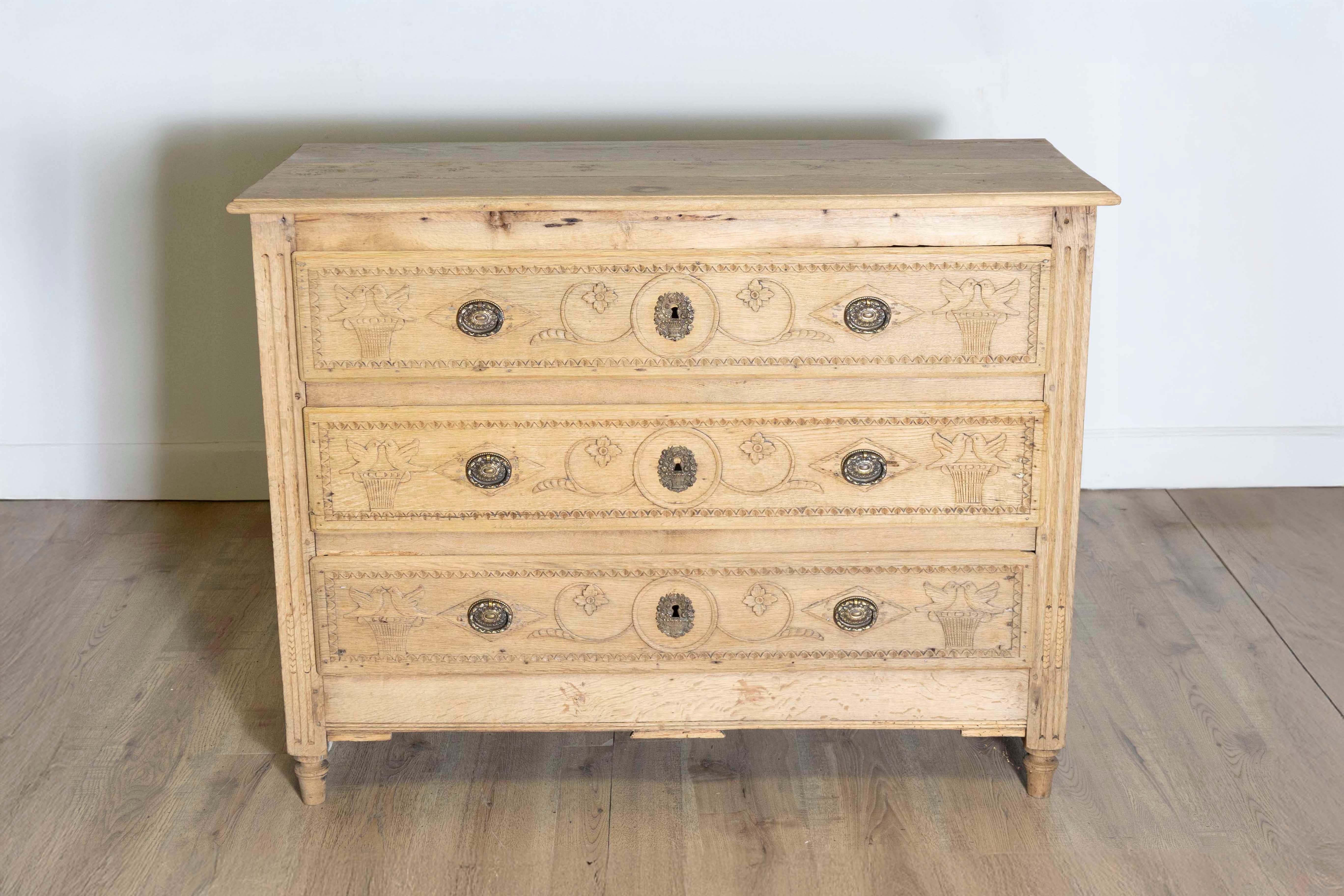 Cette commode Louis XVI blanchie du début du XVIIIe siècle, datant d'environ 1800, est une pièce magnifiquement travaillée qui illustre l'élégance et la sobriété du style Louis XVI. Fabriqué en chêne blanchi, il présente des détails complexes