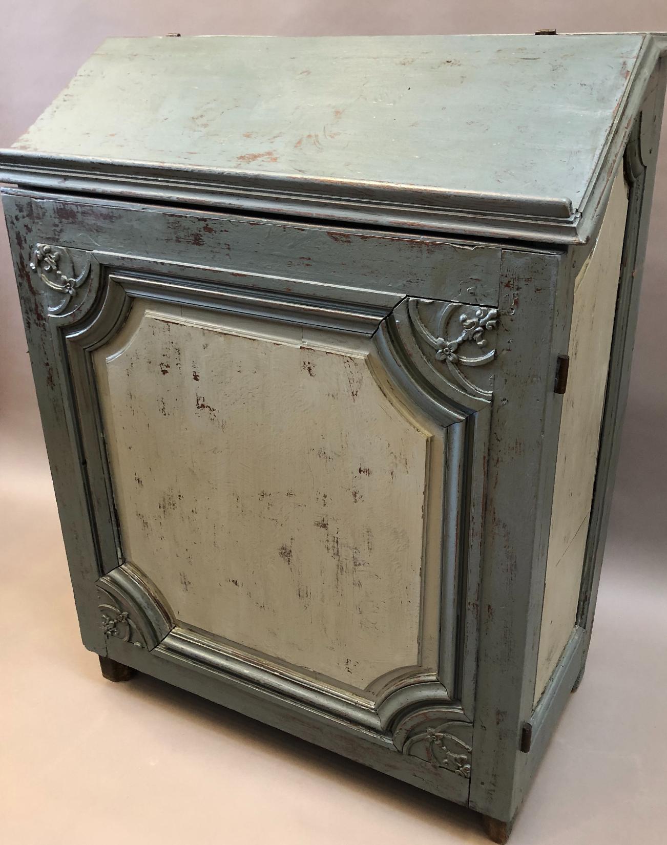 Early 18th century French provincial single door cabinet. Made predominantly of walnut and chestnut with an old blue gray painted finish. Good proportions with a single carved and paneled door below a sloped hinged book rest. Made near Poitiers