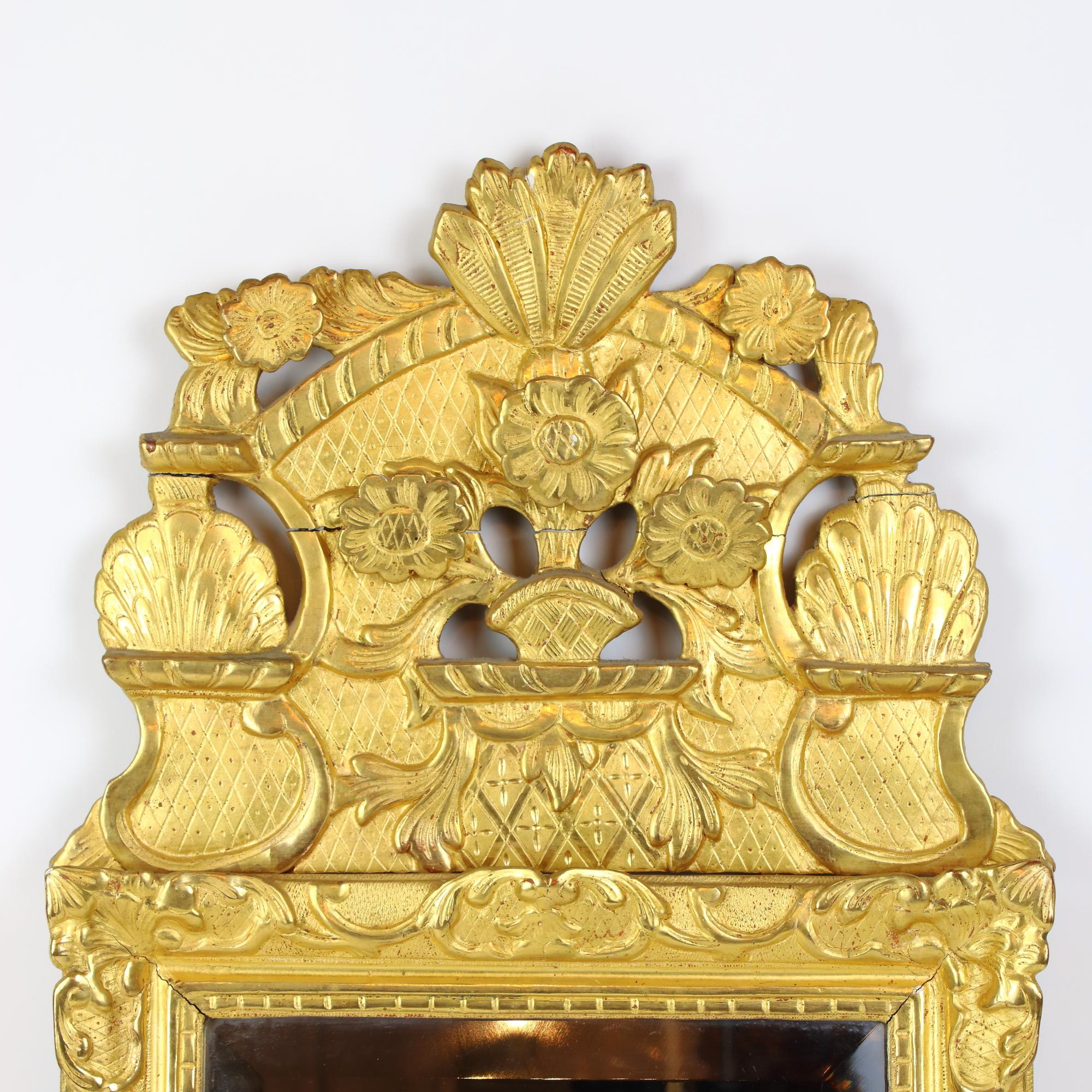 Miroir en bois doré à décor floral de Régence, début du XVIIIe siècle.

Miroir en bois doré de style Régence du début du XVIIIe siècle, contenant une glace rectangulaire (13,88 po x 11,02 po / 33,5 cm x 28 cm) dans un cadre en bois doré orné d'une