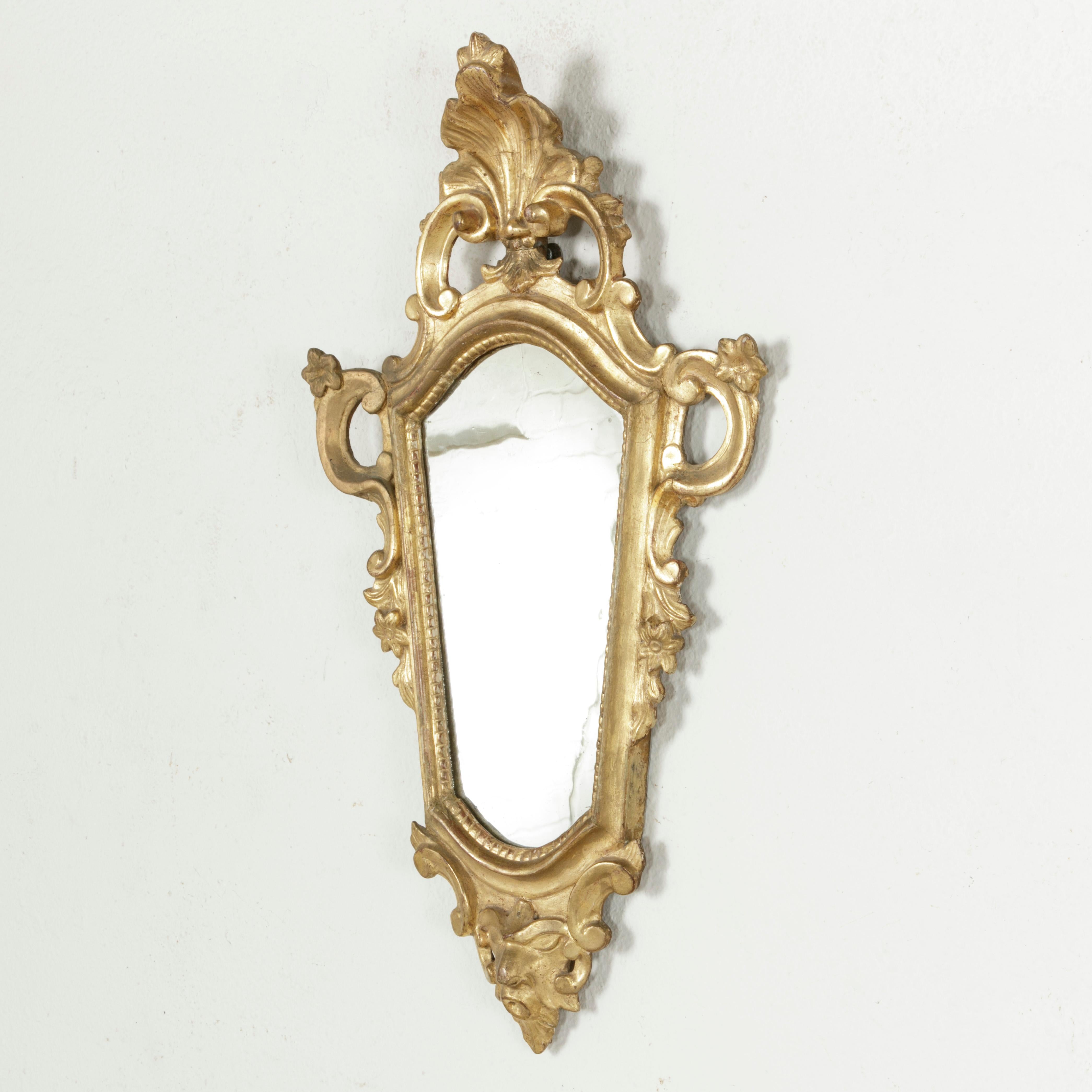 This small scale mid-18th century French Regency period giltwood mirror features its original mercury glass. Due to changes in atmosphere previously in its lifetime, a beautiful natural phenomenon of snowflake-like veining has formed in the glass.