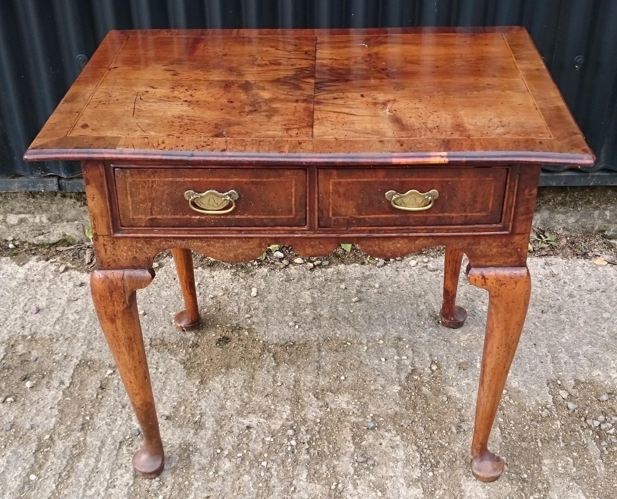 Early 18th century George I period walnut antique lowboy side table. This is a charming early side table with wonderful faded colour, slightly wobbly top, quarter cut veneers, crossbanding, stringing, a carved apron and cabriole legs. It is