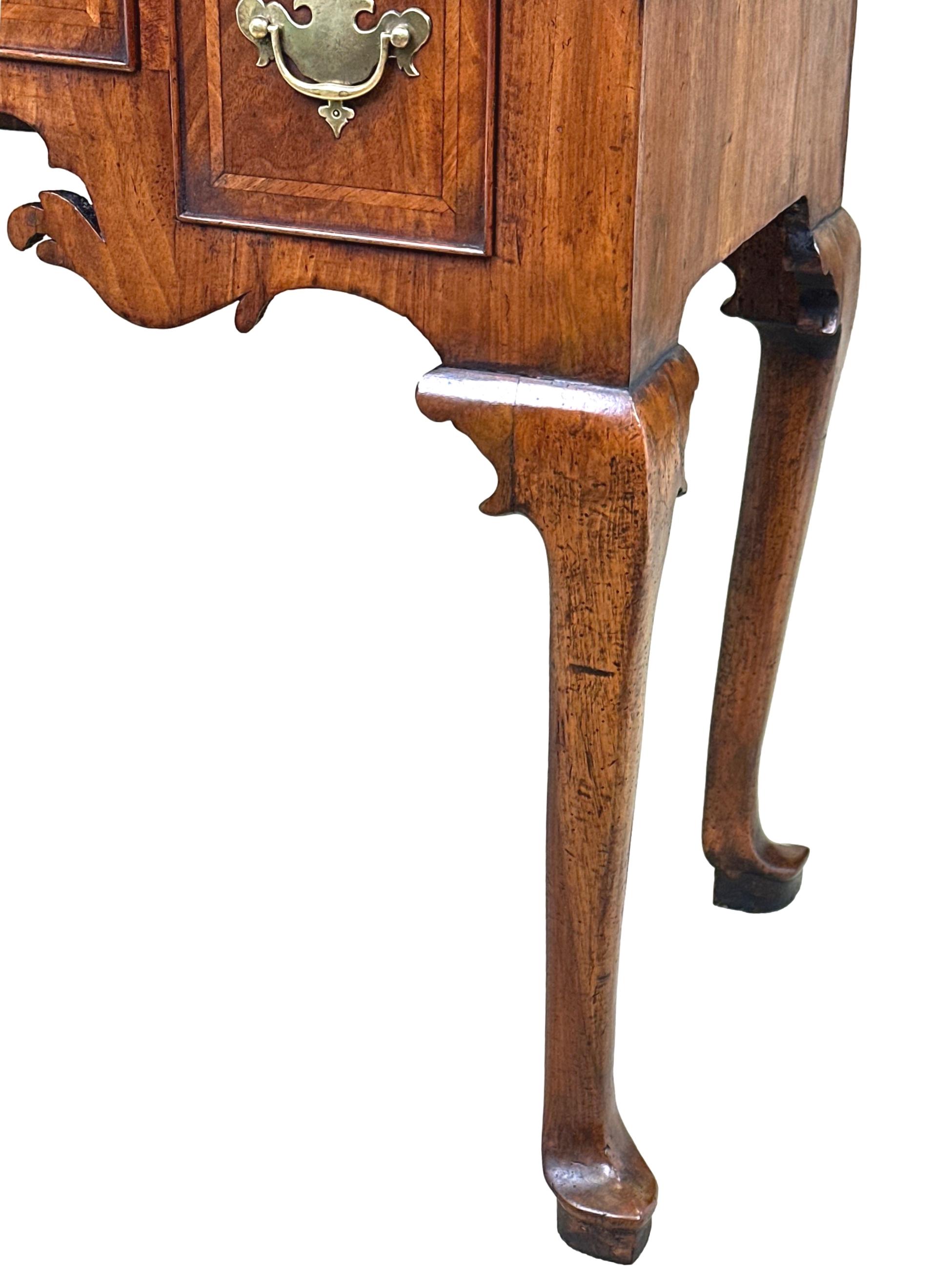 Extrêmement attrayante table basse en noyer du début du XVIIIe siècle de l'époque de George II, avec un plateau en placage de quart de cercle bien figuré et décoré de bandes, sur trois tiroirs conservant des poignées en laiton d'origine et une frise