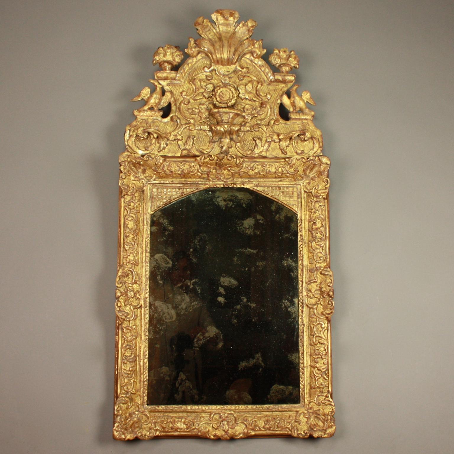 French Early 18th Century Régence Vase and Birds Cresting Giltwood Mirror

An early 18th century Régence giltwood mirror with a rectangular plate within an arched frame adorned with carved interlaced scrolls, acanthus, cabochons and foliate on a