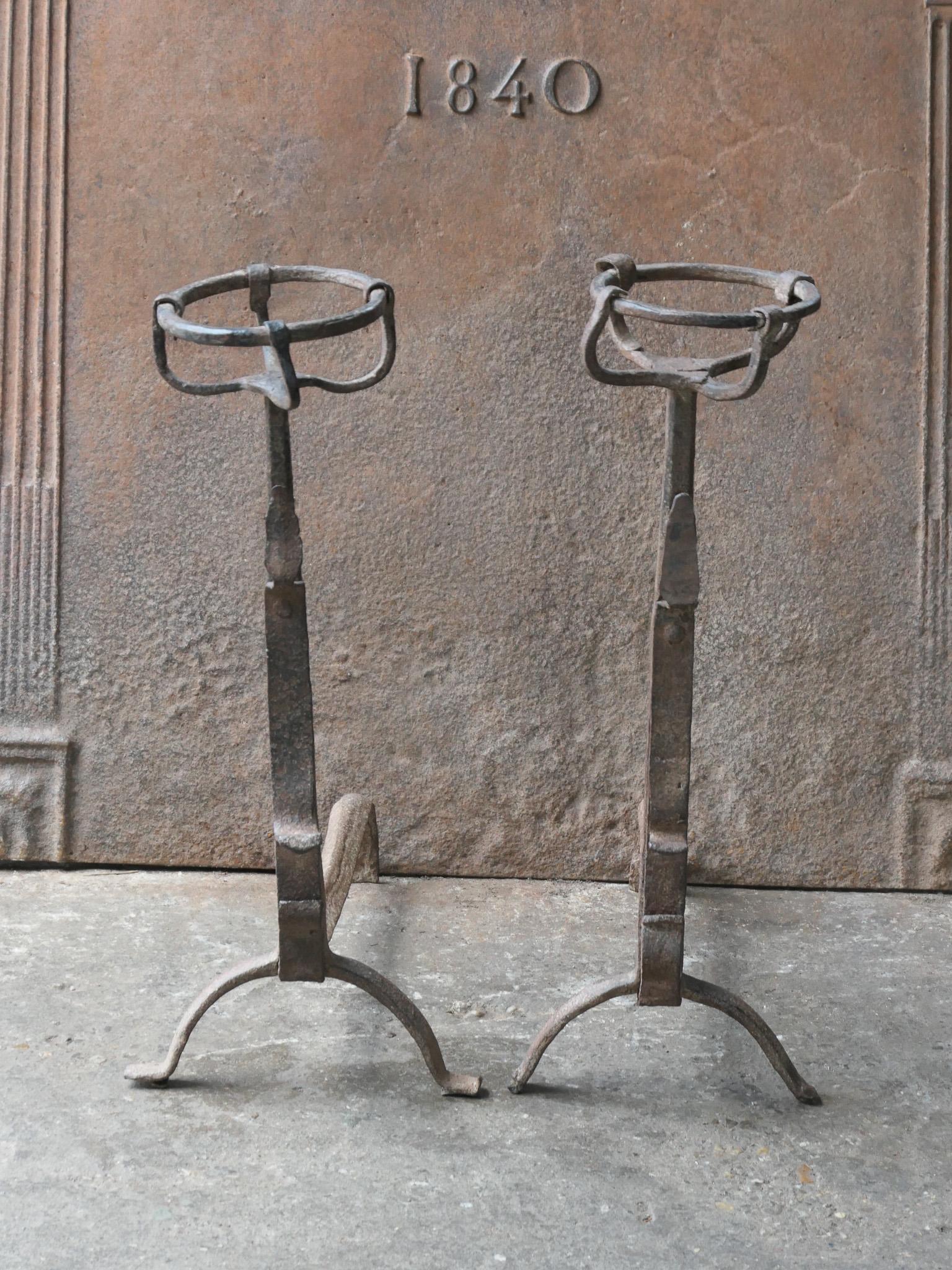 Early 18th Century French Gothic style andirons. Made of wrought iron. The andirons are in a good condition and are fully functional. With spit hooks to grill food and a cup to keep drinks or soup warm.