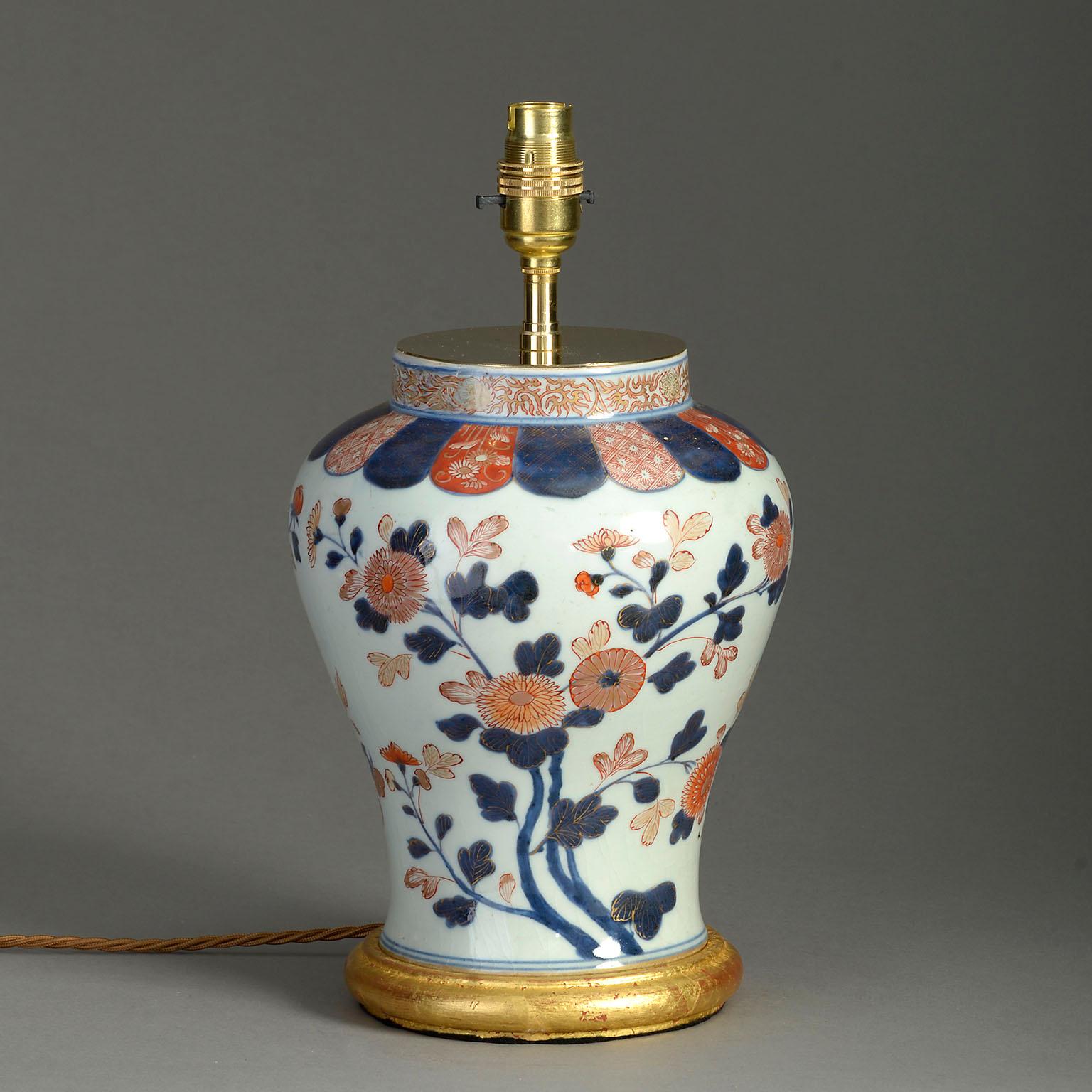 An early 18th century Imari Porcelain baluster vase of generous form, decorated with polychrome blossoms on a white ground. Now mounted as a lamp and set upon a hand-turned giltwood base.

Dimensions refer to vase and base only.

Shade not