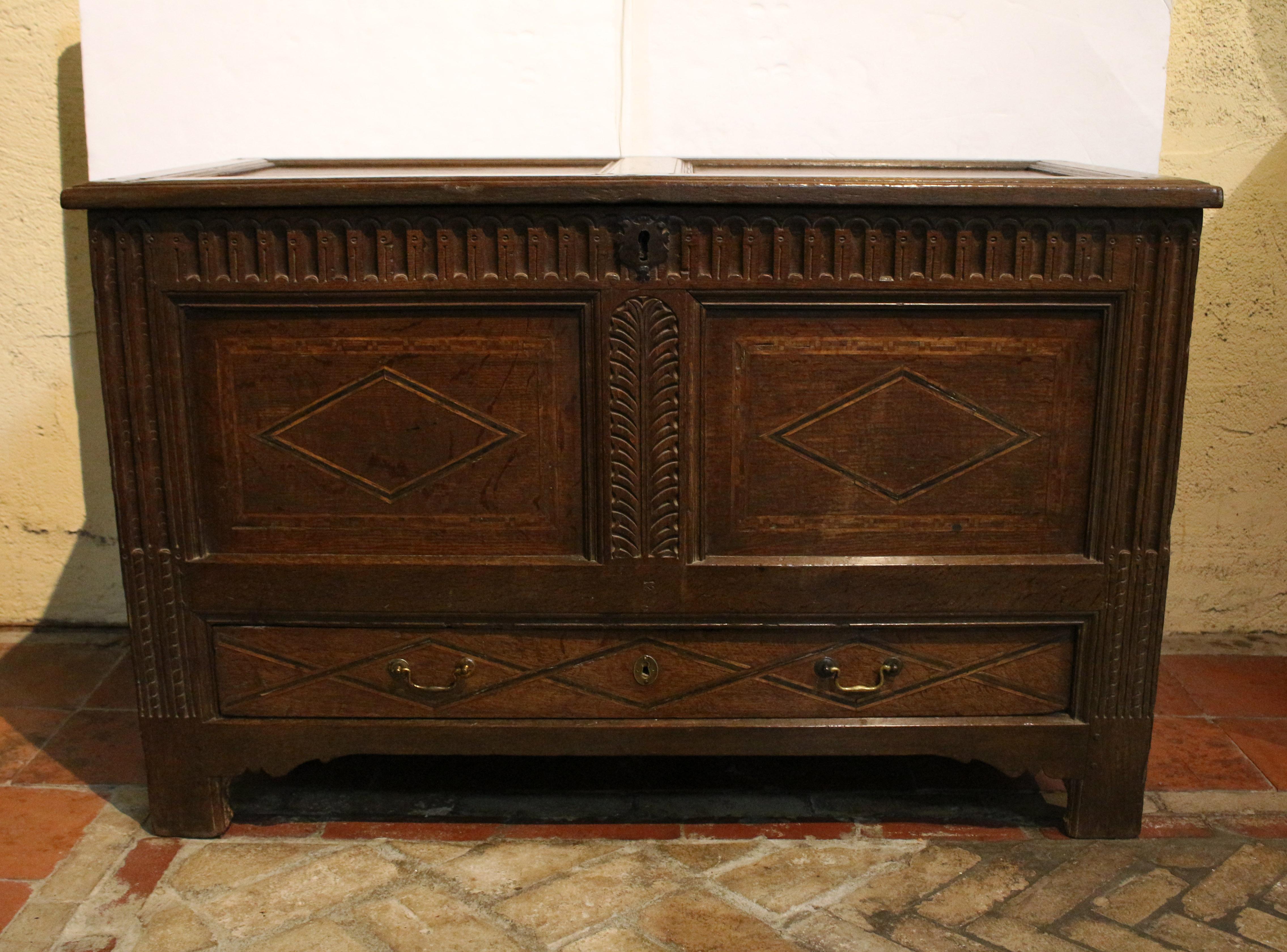 Early 18th century inlaid & carved coffer or lift top trunk, English. Coister carving across frieze beneath the well molded lift top and incorporated in elongated stop fluting form in the uprights. Diamond & parquetry inlay panels. Long bottom