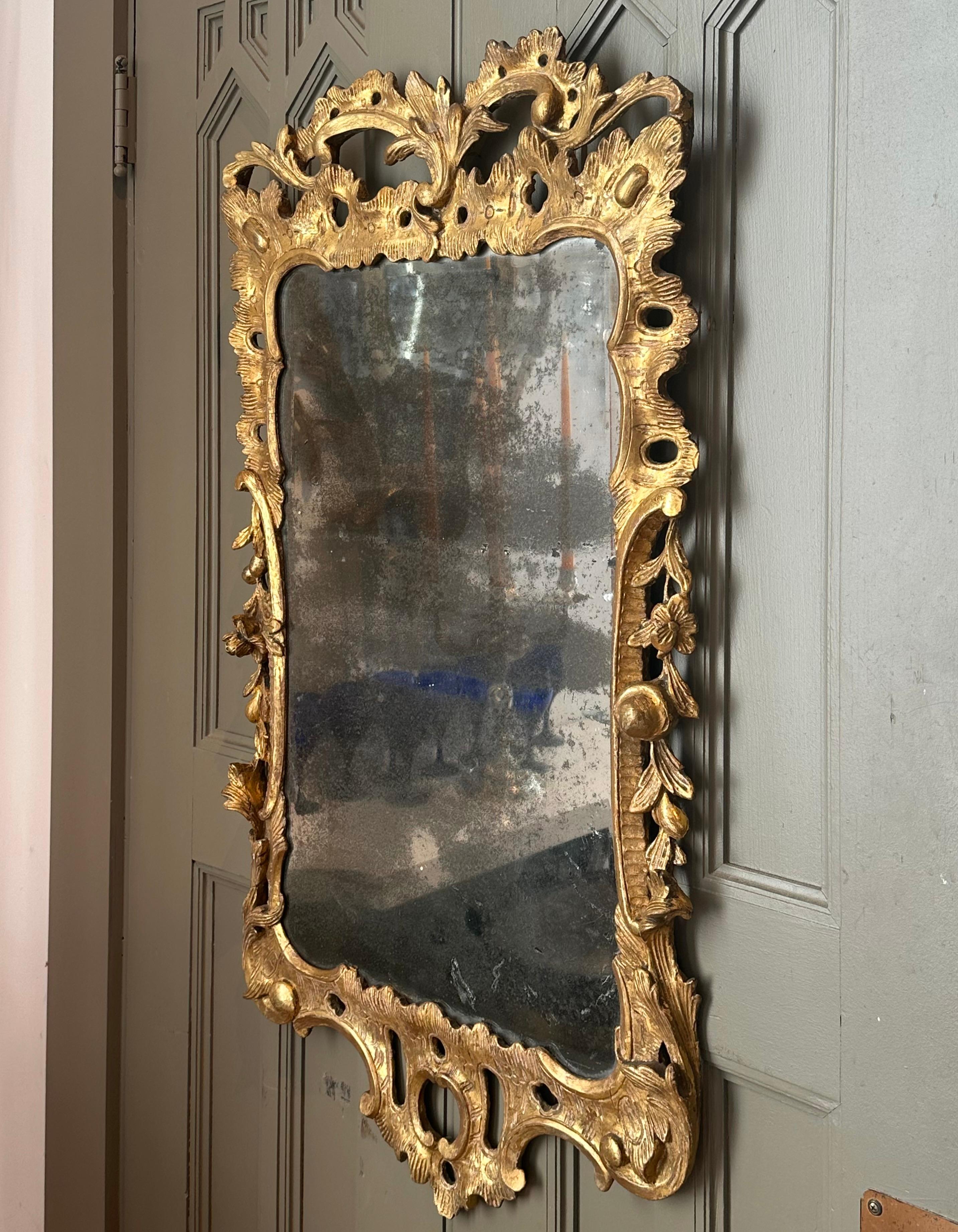 Early 18th Century Irish George II Giltwood Mirror.  Carved Rococo with foliate and fruit.  Original gilding with wear.  Original beveled mirror in magnificent oxidized state.  