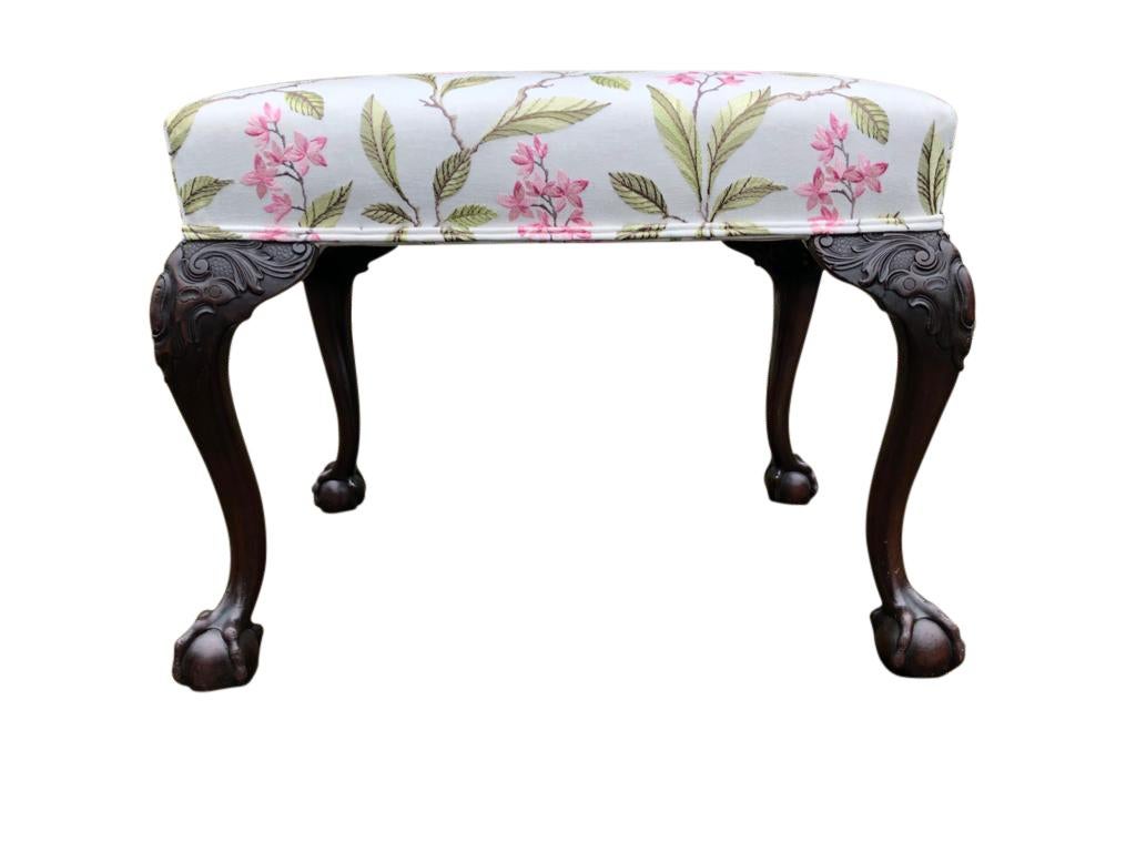 18th century mahogany carved stool. The frame has wonderfully cabriole legs with hand carved rams and foliage, ending in hairy paw feet. The superb upholstered seat is offered in immaculate condition, detailed with bright pinks and greens, on a