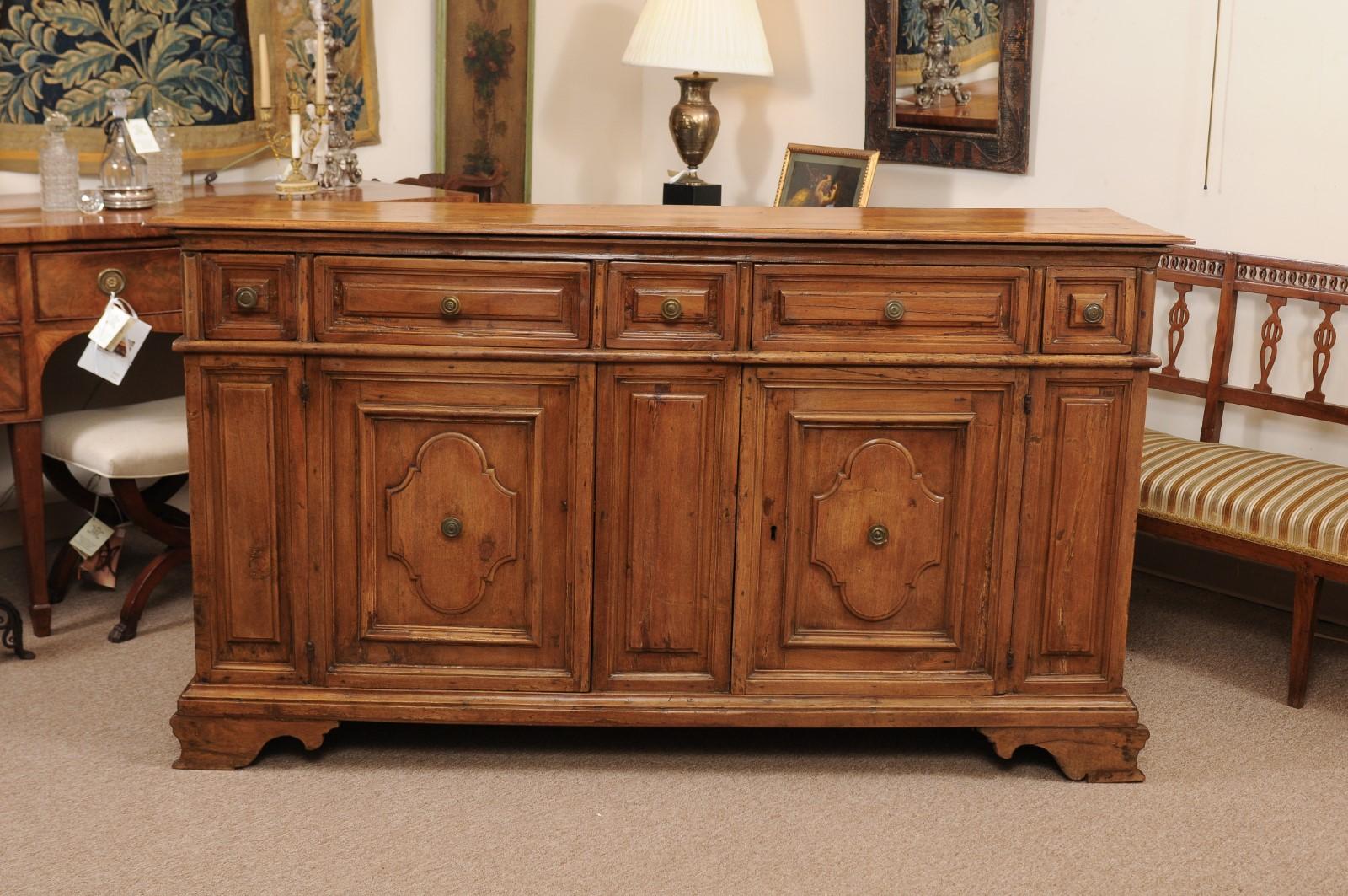 The early 18th century Italian Baroque style light walnut credenza with 5 raised paneled drawers above 2 raised paneled cabinet doors terminating in carved bracket feet. 

 