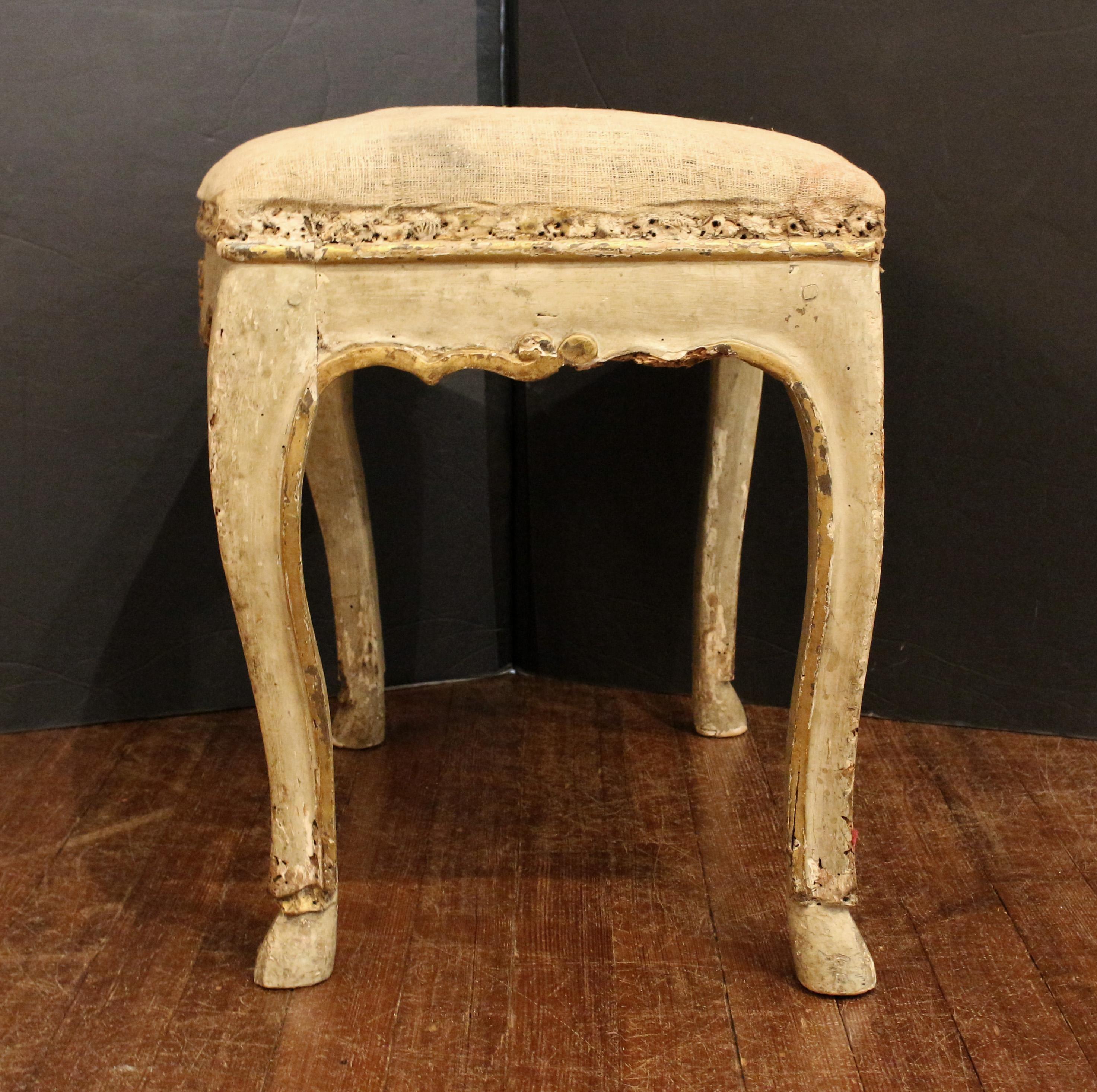 Early 18th century Italian carved, painted & gilt fireside stool. Raised on later 18th or 19th century hoof feet. Superb old layers of paint, gilding & fabric history (stripped to muslin now & ready to upholster). Multiple 20th century repairs
