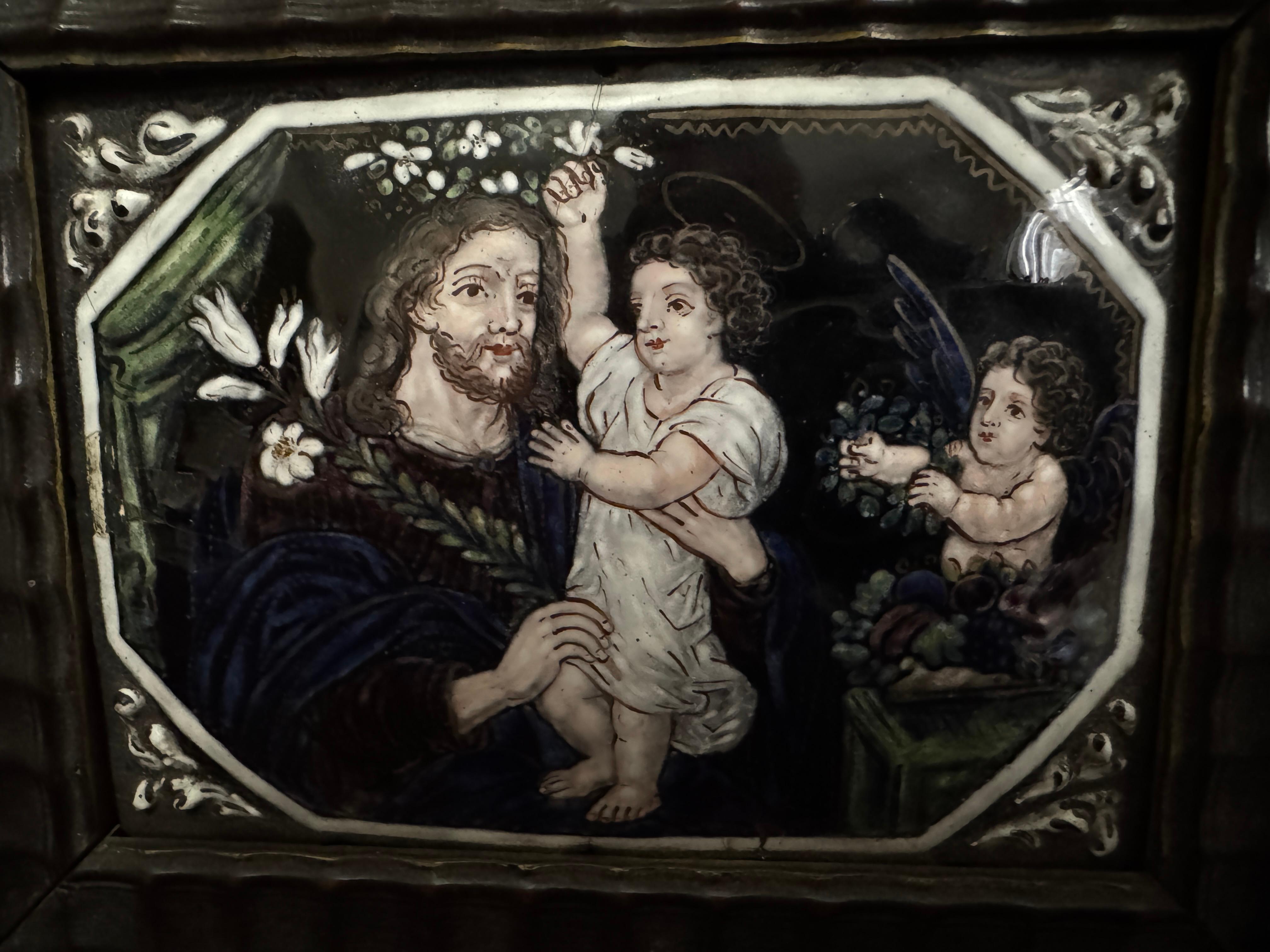 Plaque en émail de Limoges du début du XVIIIe siècle, représentant Saint Joseph couronné par l'Enfant Jésus tandis qu'un ange tient une couronne en direction de l'Enfant, les fleurs dans les coins sont estampées tandis que l'image principale est sur