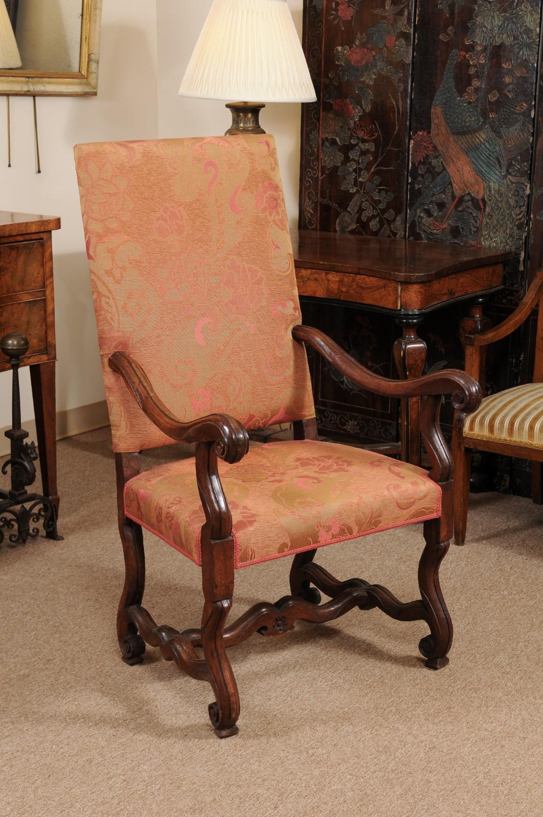 The early 18th century Louis XIV period walnut armchair with scroll arms carved mutton bone cross stretchers.