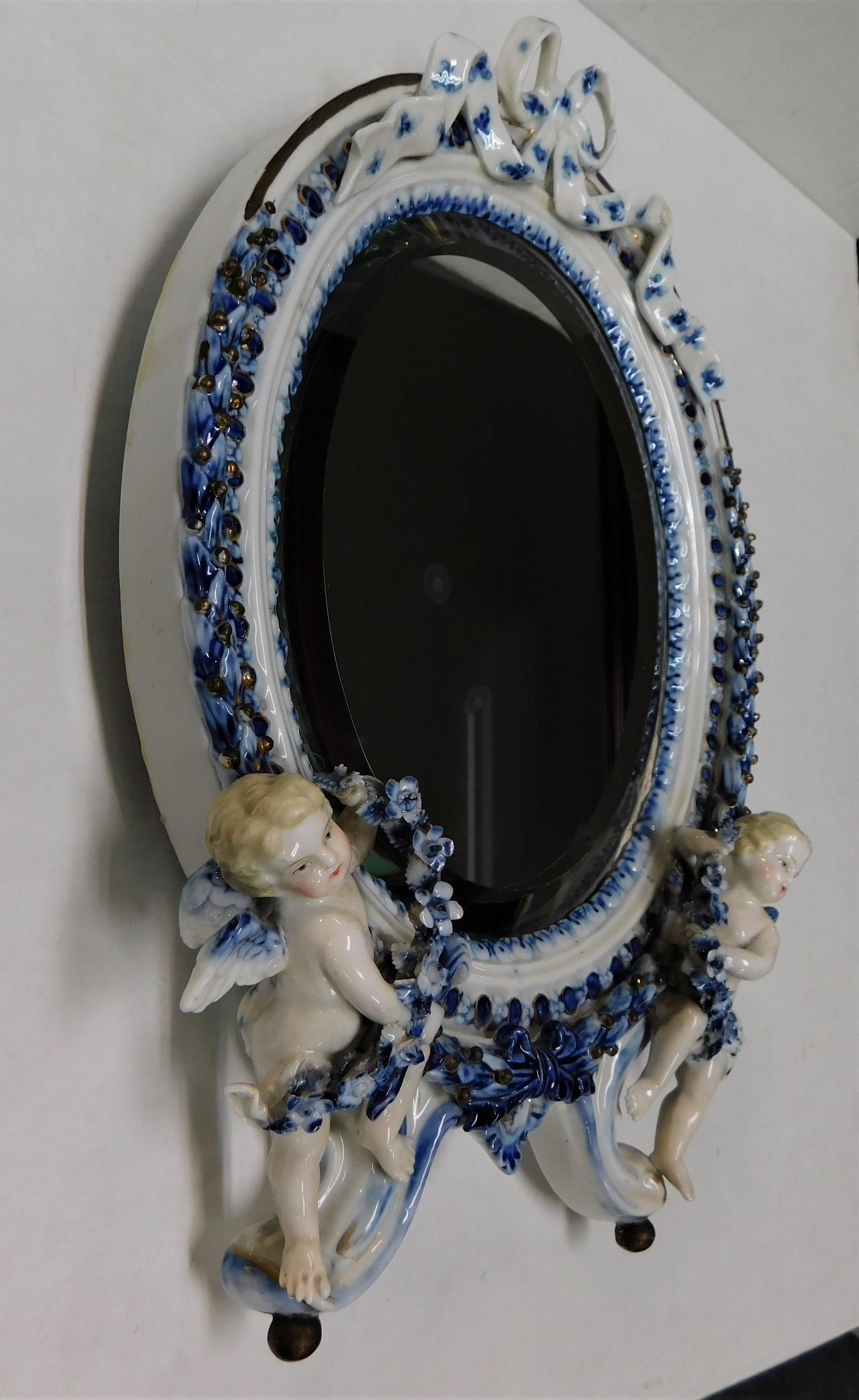 Fine German Meissen porcelain beveled wall mirror with a pair of figural cherubs. Finely modelled as an elegant 18th century piece of art, hand painted white porcelain china with cobalt blue underglaze moulded and gilded with Rococo scroll. Set upon