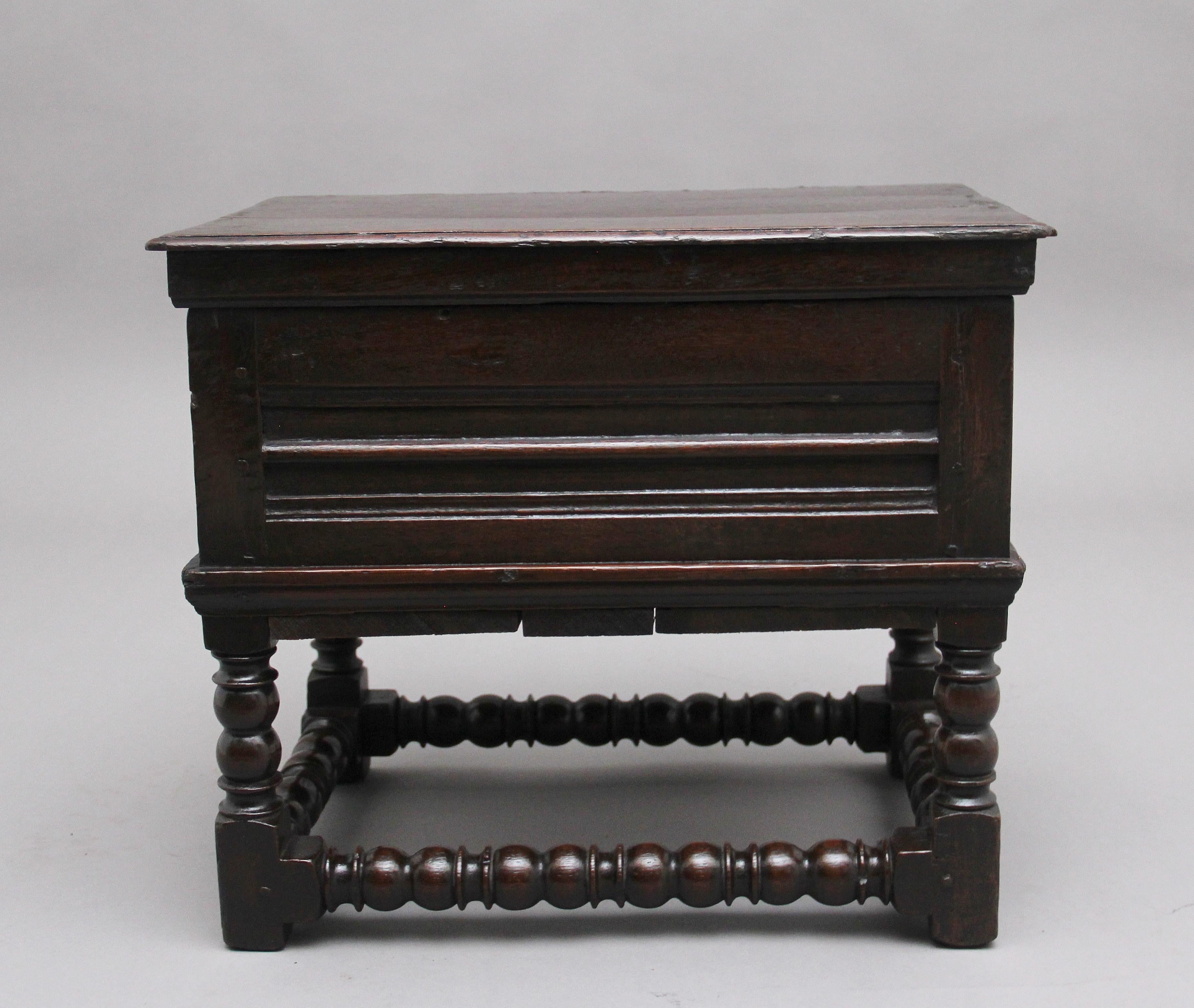 Early 18th century oak box stool, the moulded edge hinged top opening to reveal a large compartment space, moulded panels below on the front and sides, supported on bobbin turned legs and stretchers. Circa 1740.
 