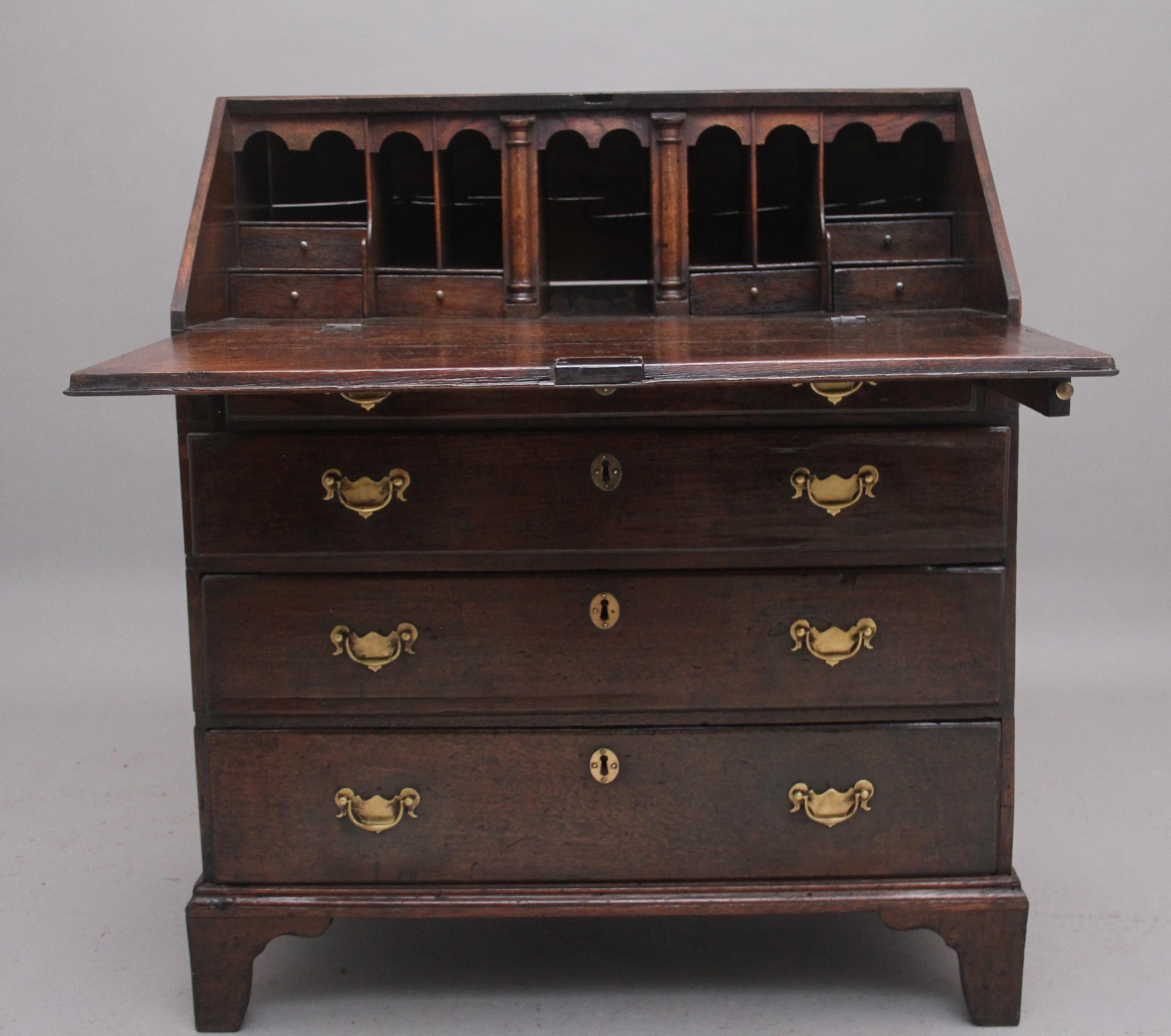 Early 18th century oak bureau, the fall opening to reveal a lovely fitted interior with various drawers, pull out slides and compartments, the bureau having four graduated drawers with brass plate handles and escutcheons, standing on bracket feet.