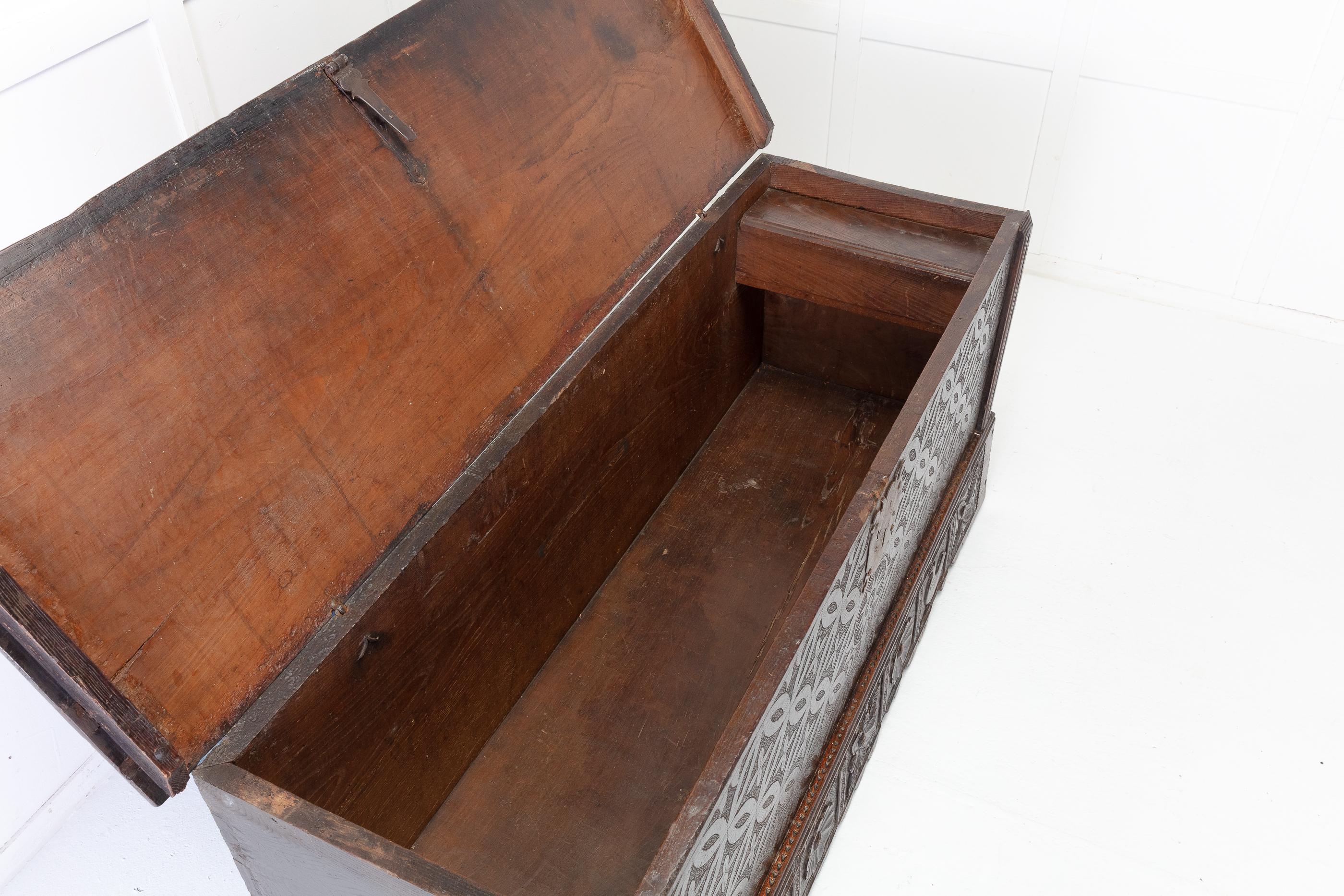 Early 18th century oak coffer on a carved plinth base. Having a single piece, overhanging hinged lid with moulded edges, which opens to reveal storage space and a small boxed compartment on the inside right.
It has its original iron lock and large