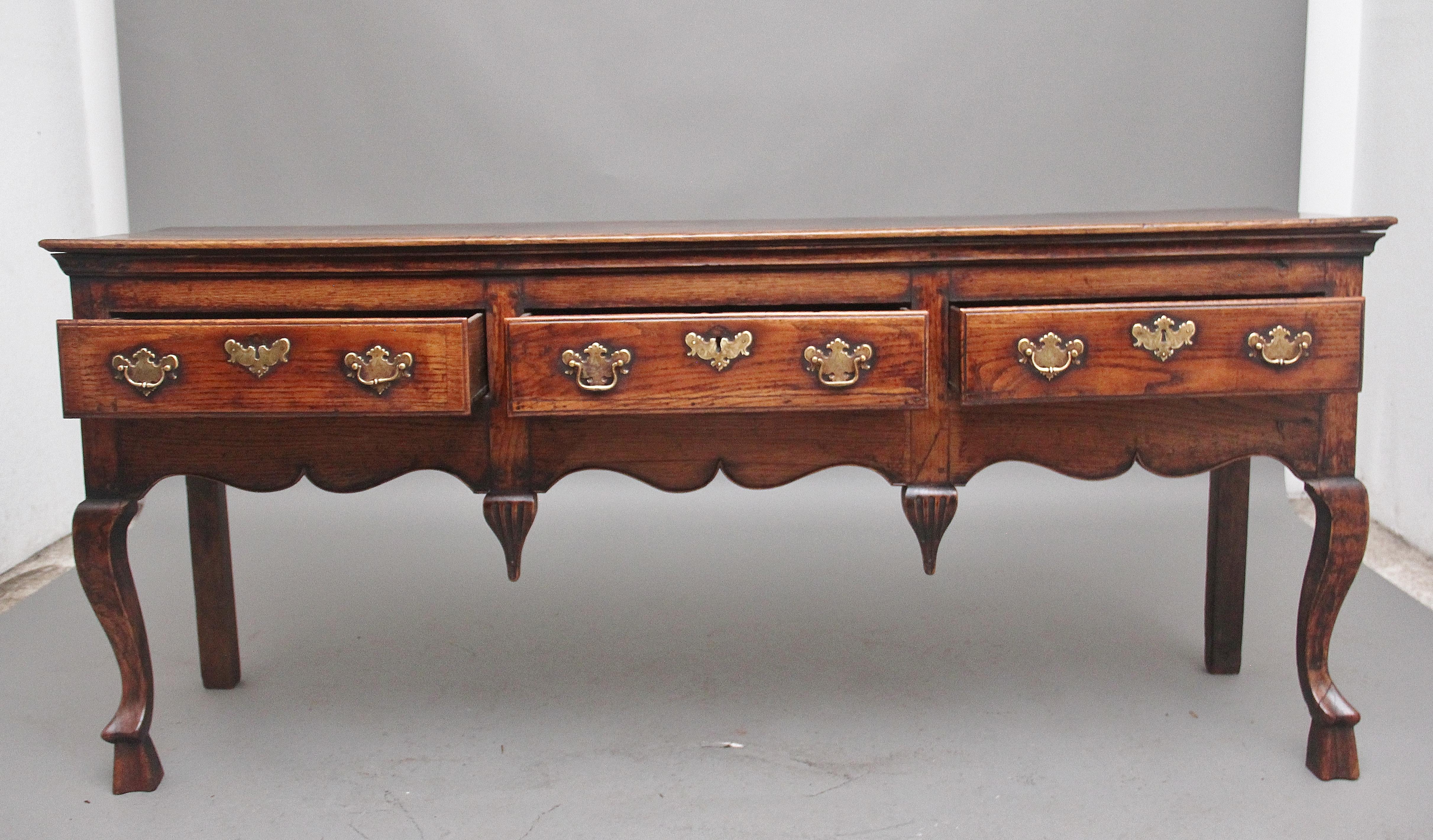 A superb quality and rare early 18th Century oak dresser, the moulded edge top above three drawers with the original brass handles and escutcheons, a wonderfully shaped frieze decorated with inverted finials, supported on elegant cabriole legs