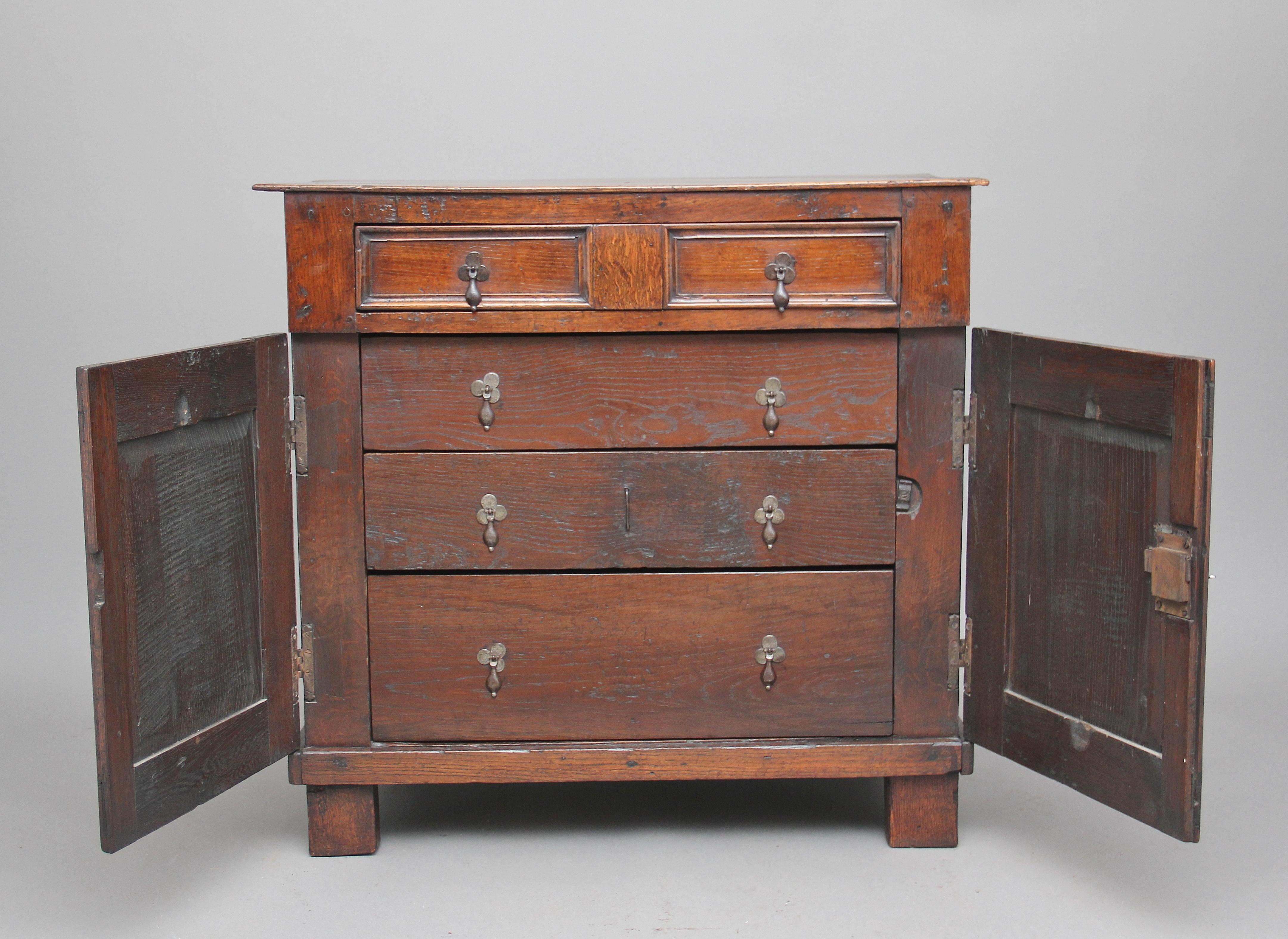 Early 18th century oak cupboard / enclosed chest of drawers of good proportions, the lovely figured top above a frieze drawer with brass drop handles, the drawer fronts having a nice moulded edge, two panelled cupboard doors below opening to reveal