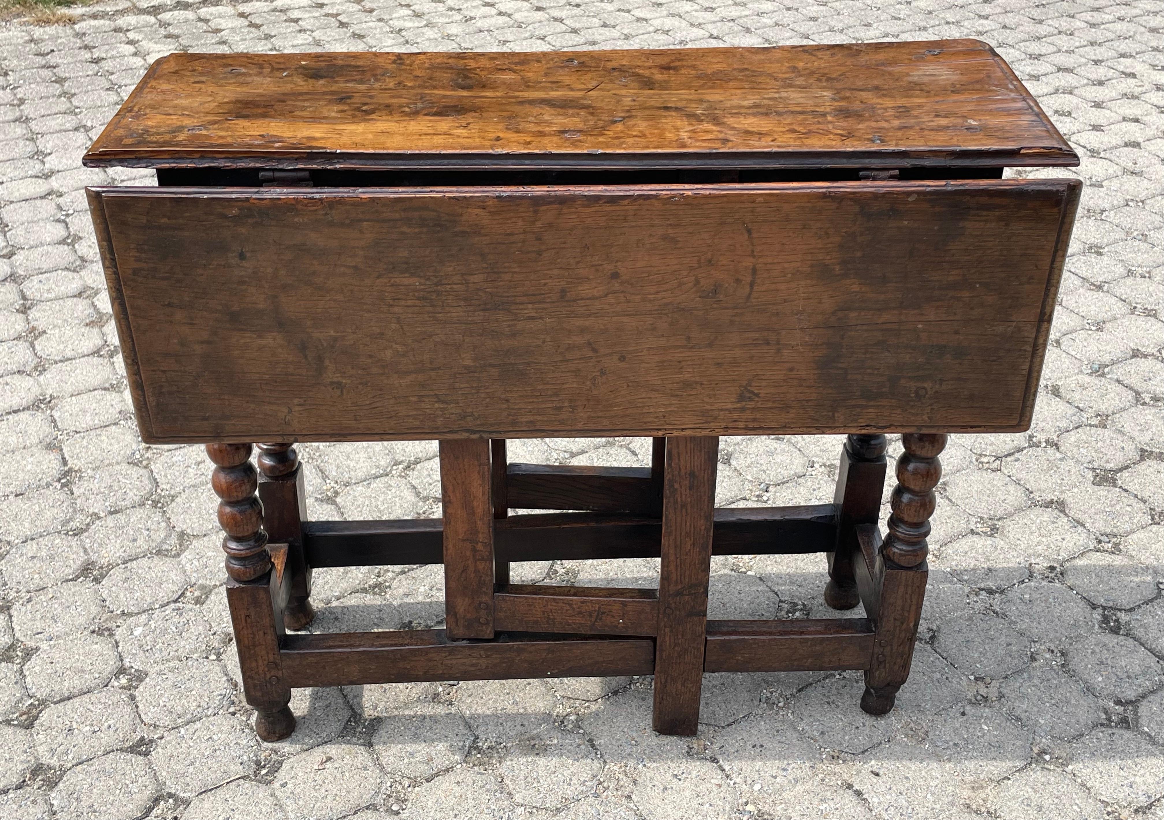 Early 18th century oak gateleg table of diminutive size.  With carved bobbin legs and great color.  Unusual rectangular drop leaf element suggests an earlier date.