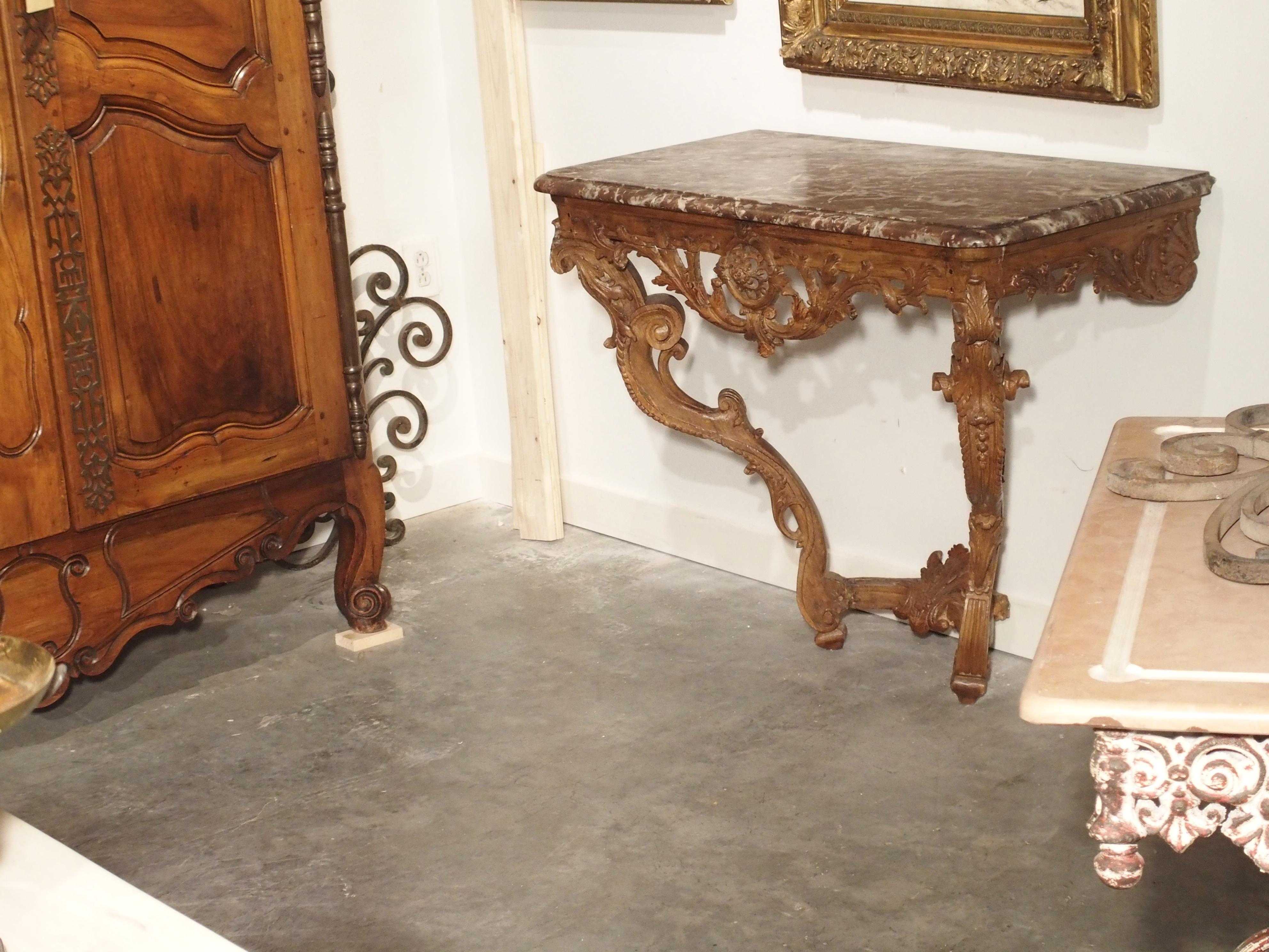 This is a very fine, period French Regence oak console with a rouge marble top. The rectangular frieze has hand carved scrolling acanthus leaves extending to either side of a central circular motif. This motif is reticulated into 8 larger circles