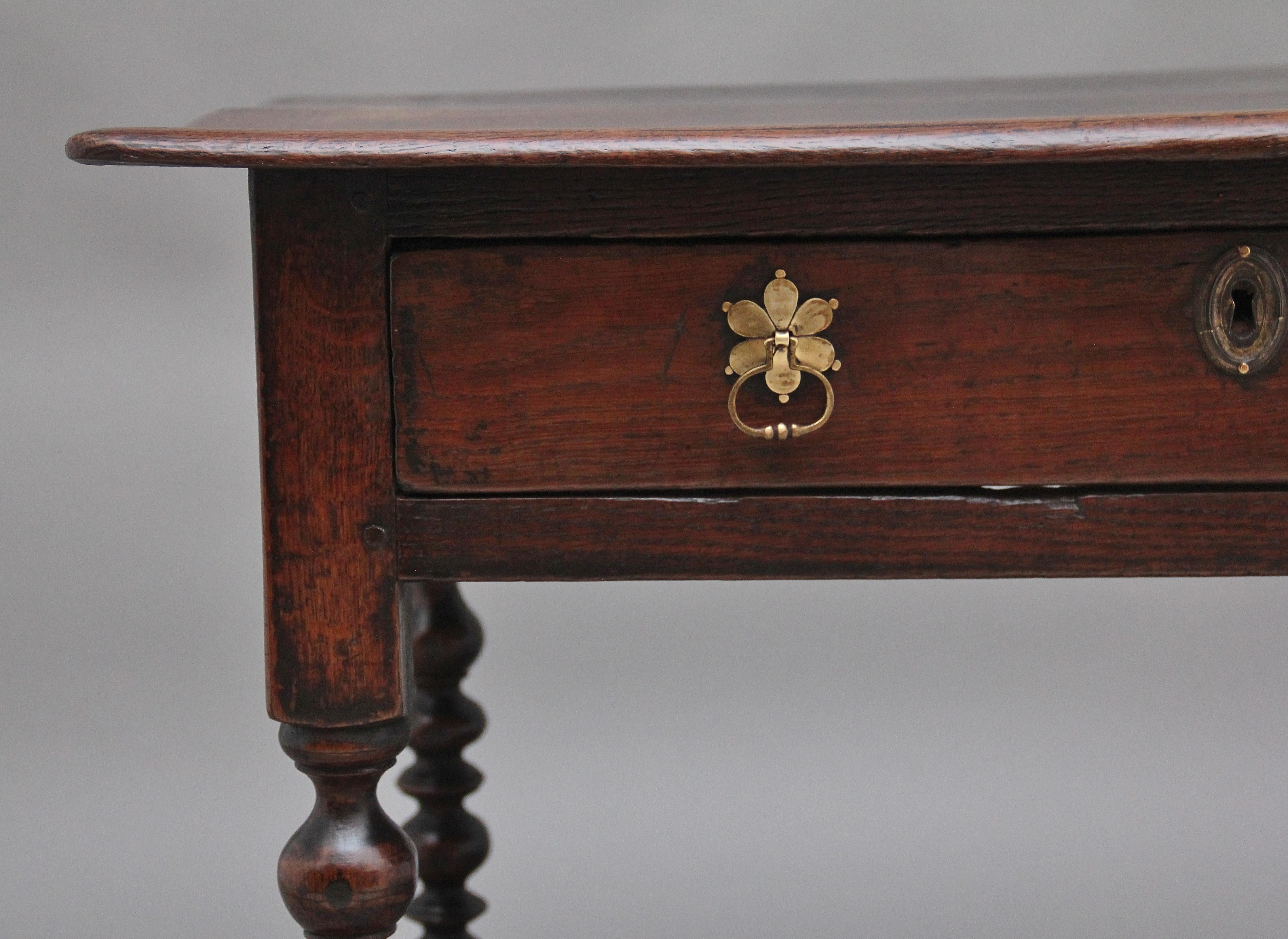An early 18th Century oak side table, having a nice figured rectangular top above a single oak lined frieze drawer with brass petal shaped drop handles and escutcheon, raised on turned barley twist legs on block feet feet united by stretchers. 
