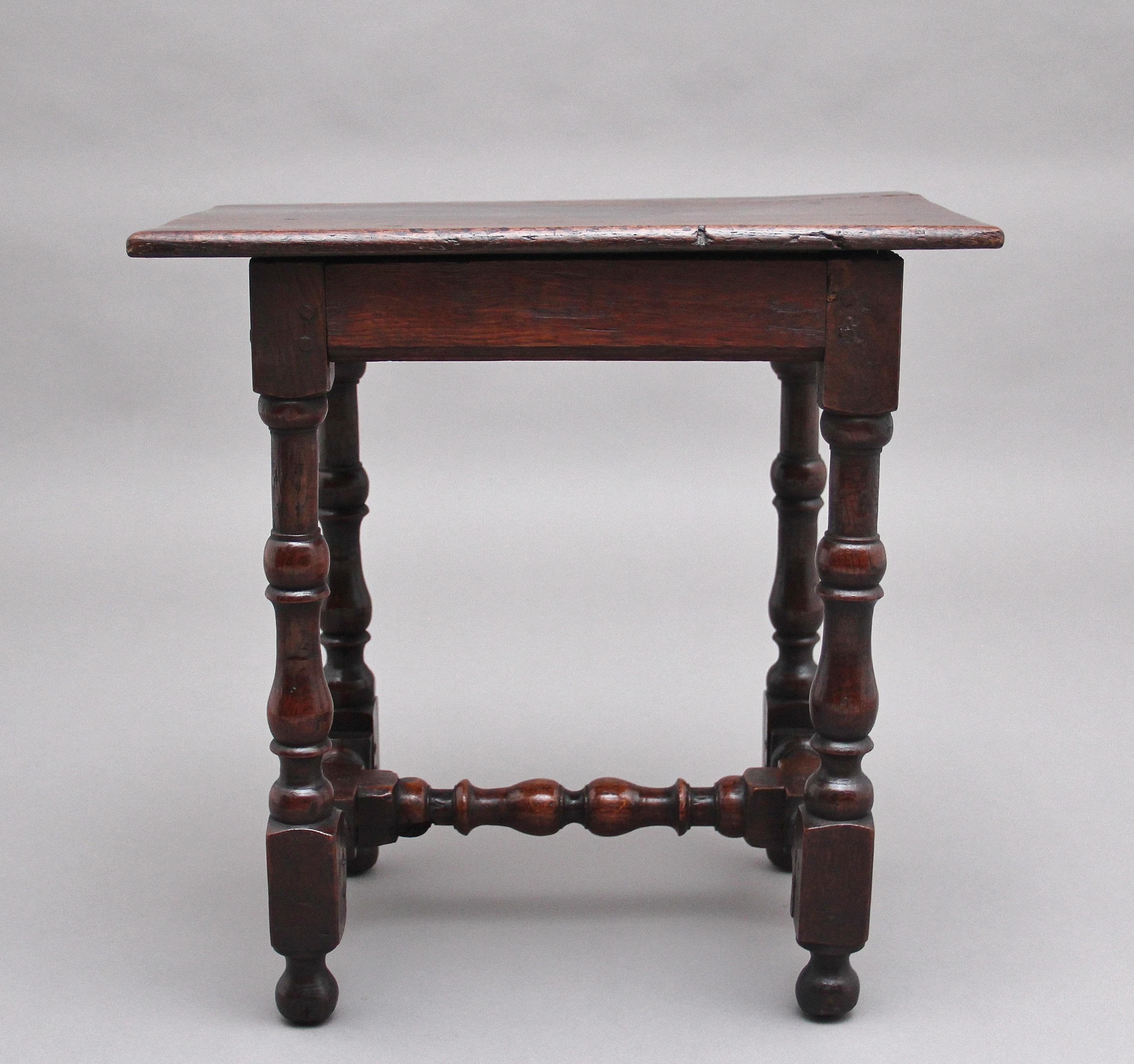 Early 18th century oak stool, the rectangular solid rustic top above a frieze with a moulded edge, supported on four turned legs united a block and turned stretcher. Circa 1740.