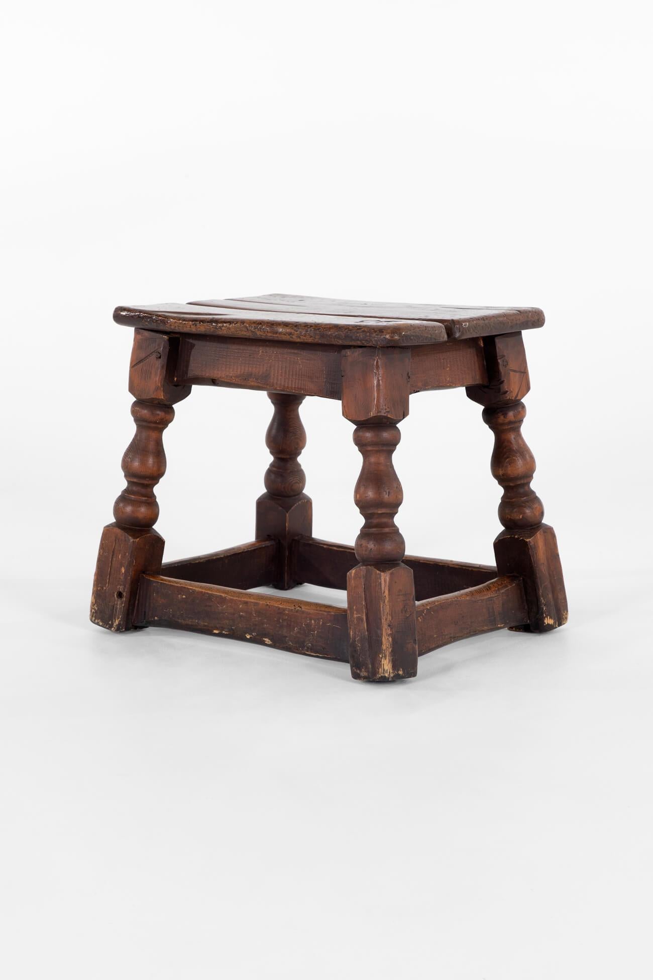 A charming 18th-century low oak stool.

The characterful two-plank top is raised upon four sweeping turned legs finishing on block feet and united by a peripheral stretcher.

Great colour and patination with an interesting branding or carving to the