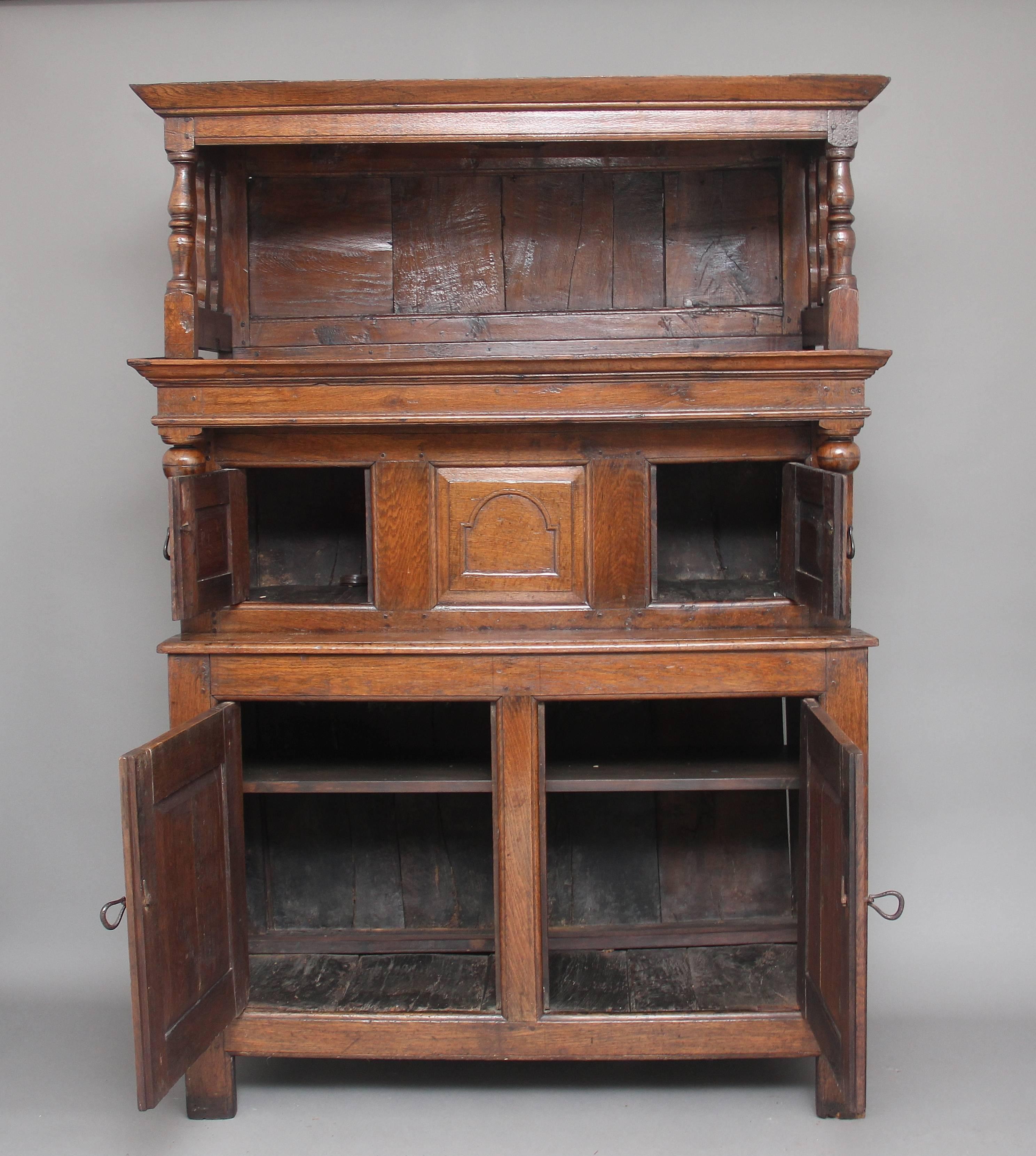 Early 18th century oak tridard / court cupboard in three sections, the open top section supported on turned columns above the middle section with two fielded panel doors each side of a central arched fielded panel, lovely turned finial decoration