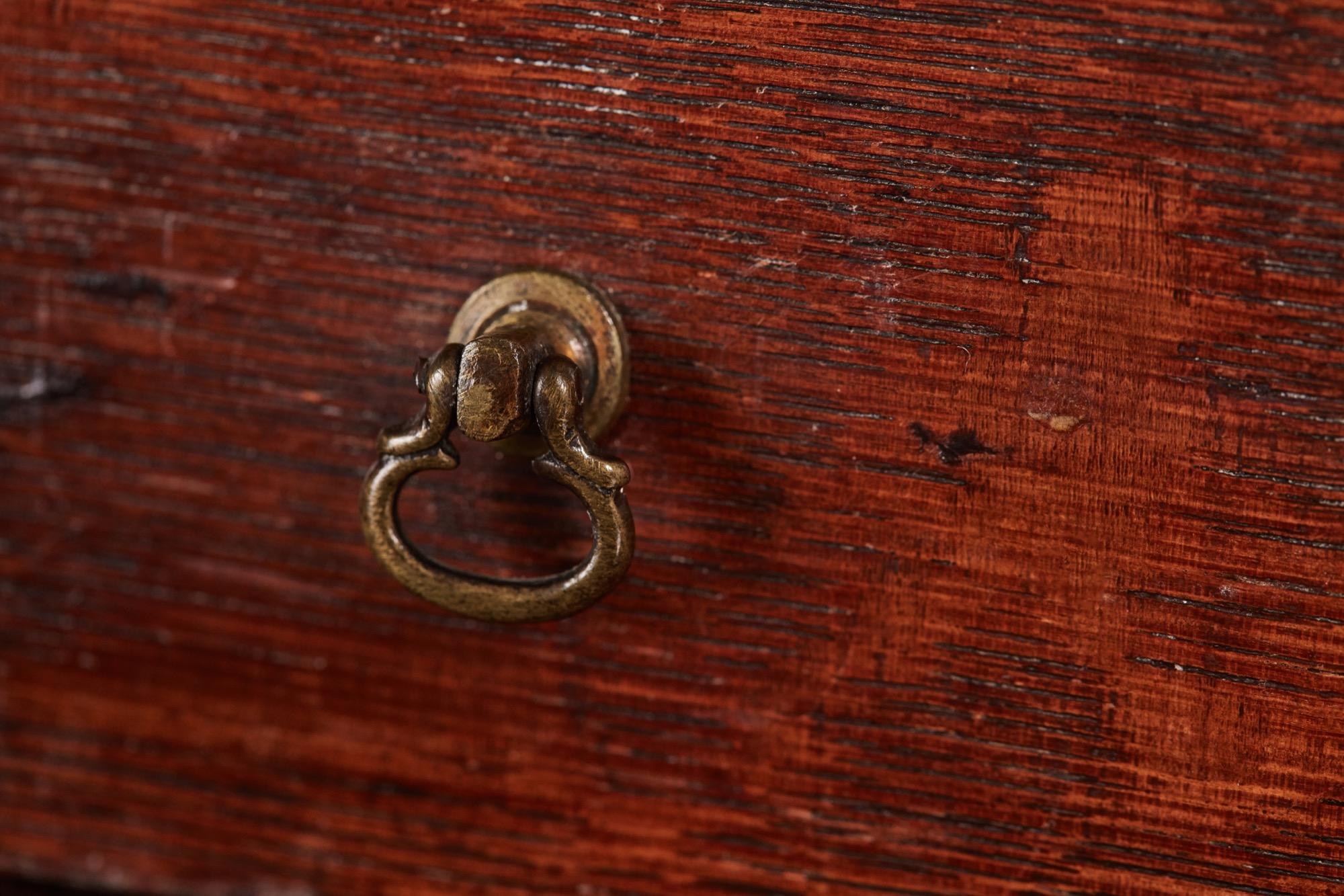 Early 18th century oak welsh dresser base with four drawers and original brass handles. This exceptional piece has two cupboard doors each with raised shaped panels and a center raised panel. Three drawers with original brass handles, splendid