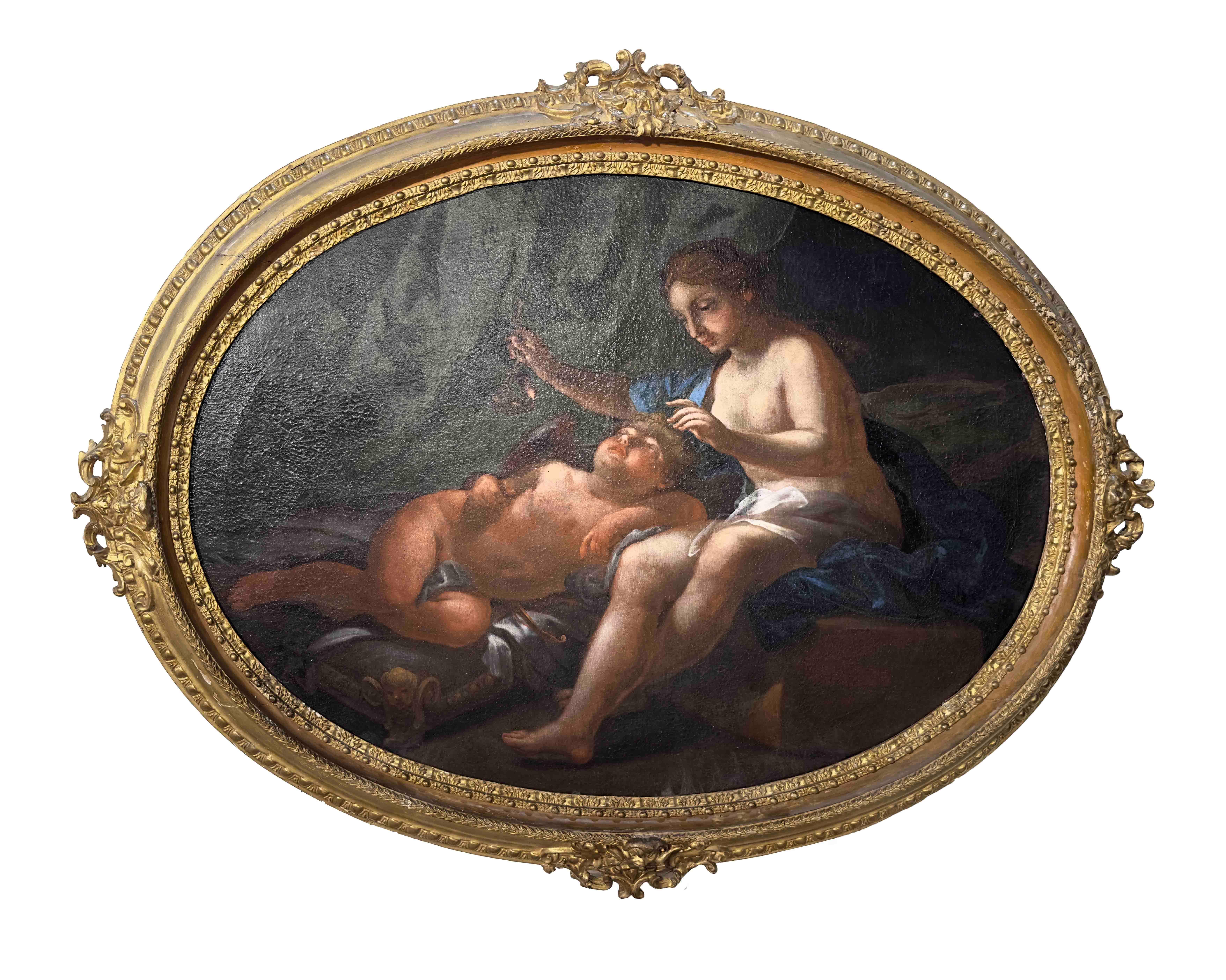 This beautiful oval painting, created using the oil on canvas technique, features a horizontal orientation and depicts the goddess Venus half-naked and sitting on a stool, while she watches over her son Cupid sleeping on a small bed. The goddess