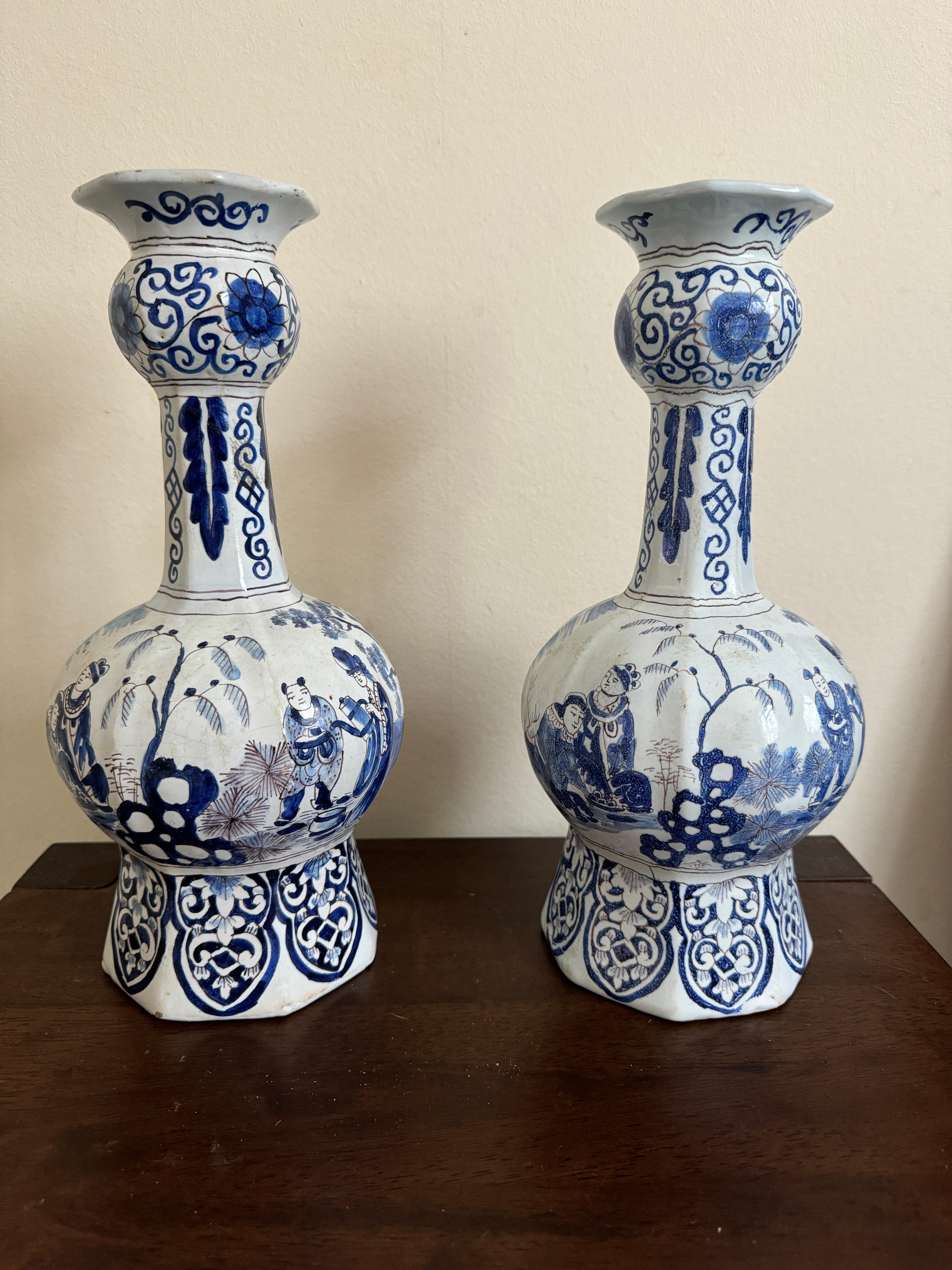 Paire de vases de Delft du début du 18e siècle, de forme balustre octogonale avec des cols en forme d'ail, peints en bleu avec des figures de Chinoiserie dans un paysage à l'intérieur de bordures de feuilles, de rinceaux et de panneaux, marque D.
