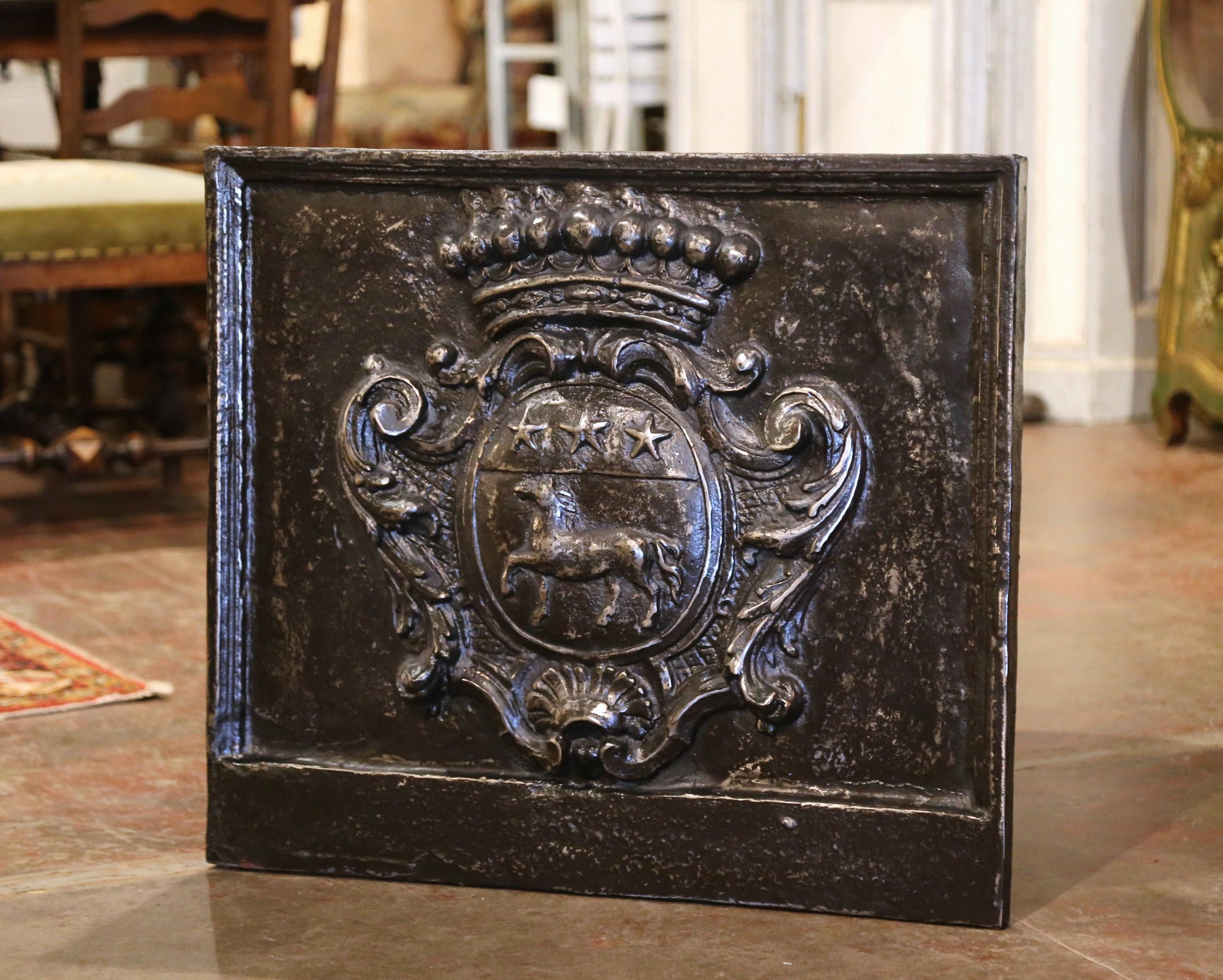 Decorate your fireplace with this elegant antique Regence Period fire back. Crafted circa 1720 and almost square in shape, the French ornate fireplace essential, features a family crest in very high relief, decorated with horse and star motifs and