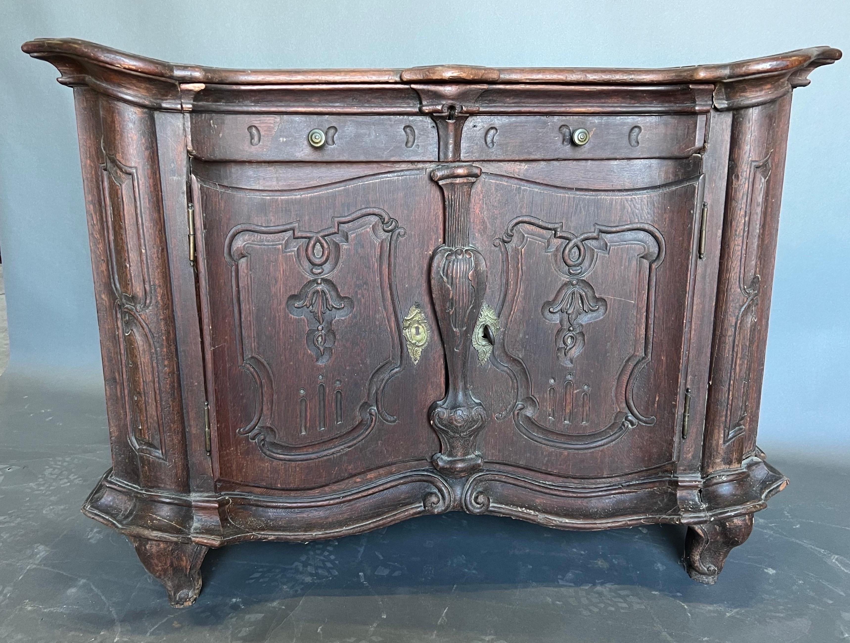 What a beauty this early 18th century Portuguese rococo cabinet is. Lovely proportions, shaped top and Rosehead mail construction throughout. One drawer over two doors with the entire piece resting on an early, primitive form of cabriole feet