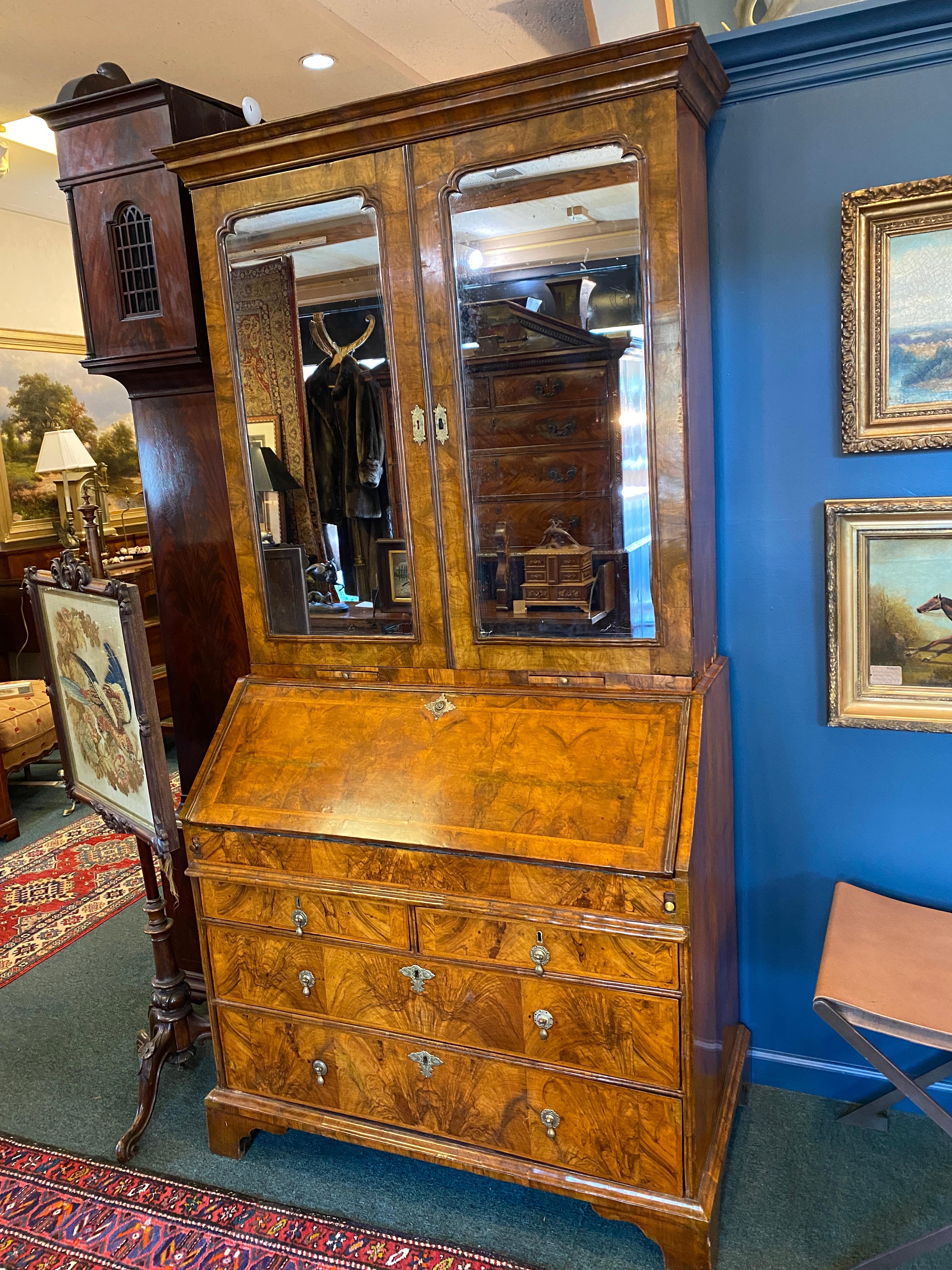 Early 18th century Queen Anne Period walnut Bureau bookcase. The rich color and original condition of this piece are outstanding. Beneath the molded cornice the two mirrored doors retain their original shaped plates and enclose adjustable shelves