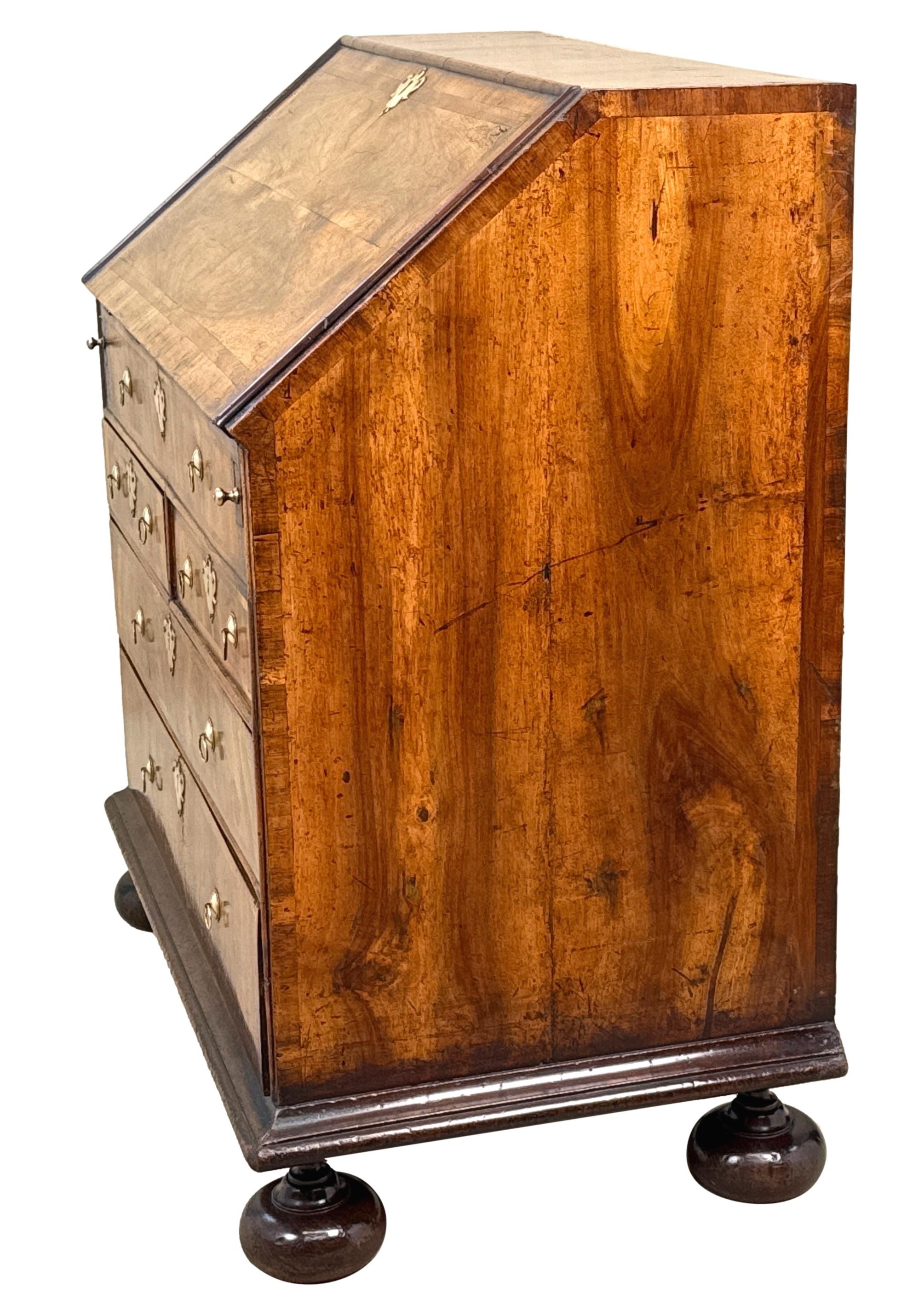 Encantador escritorio de nogal de principios del siglo XVIII, de la época de la reina Ana, de muy buena calidad, con tapa y solapa magníficamente labradas, decoradas con bandas de plumas, que encierra un atractivo interior equipado con palomares,