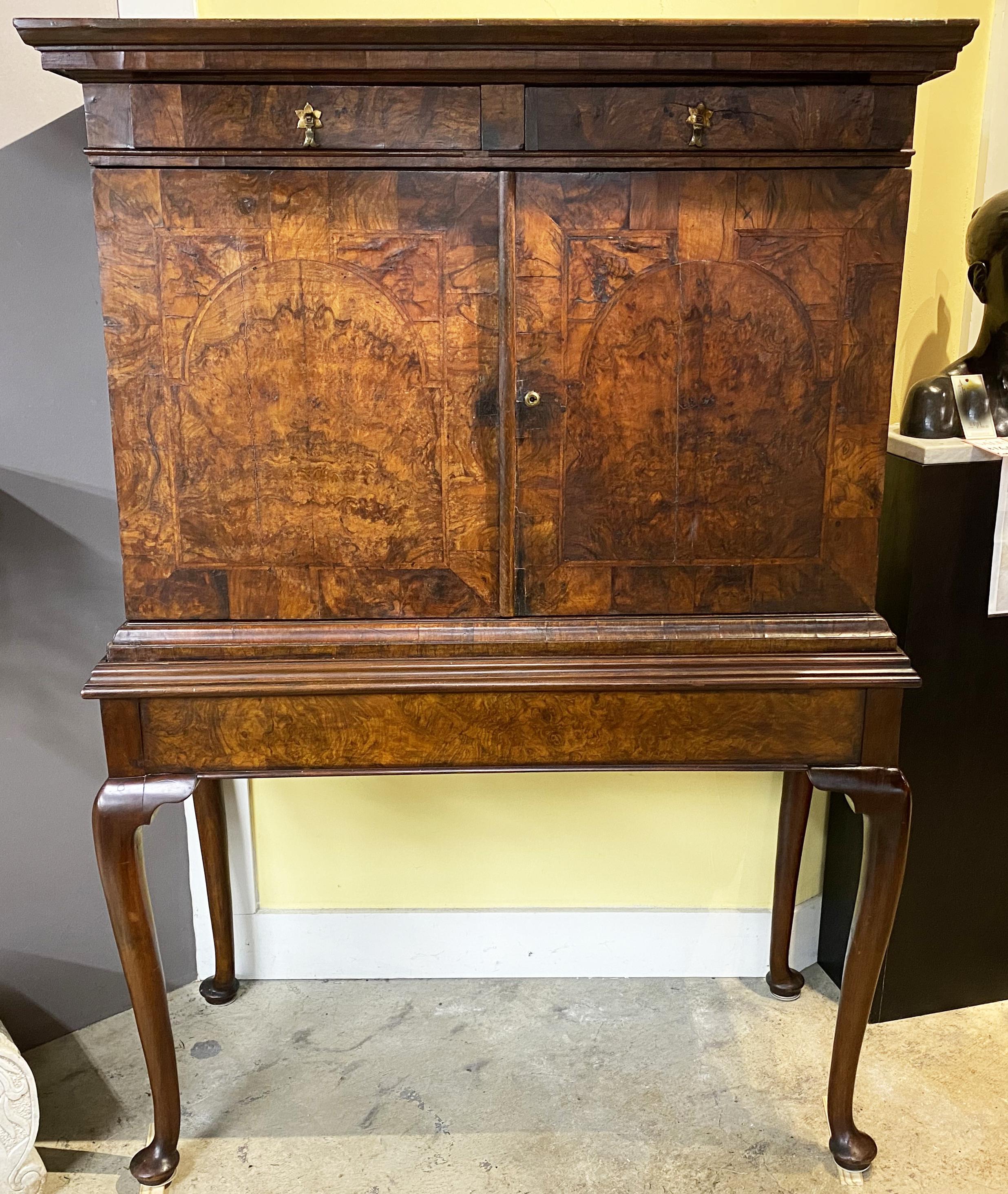 A wonderful English Queen Anne walnut and burled walnut two part collector’s cabinet, its upper case with a molded cornice surmounting a case with two upper fitted drawers over two doors with beautiful burled walnut veneers which open to a